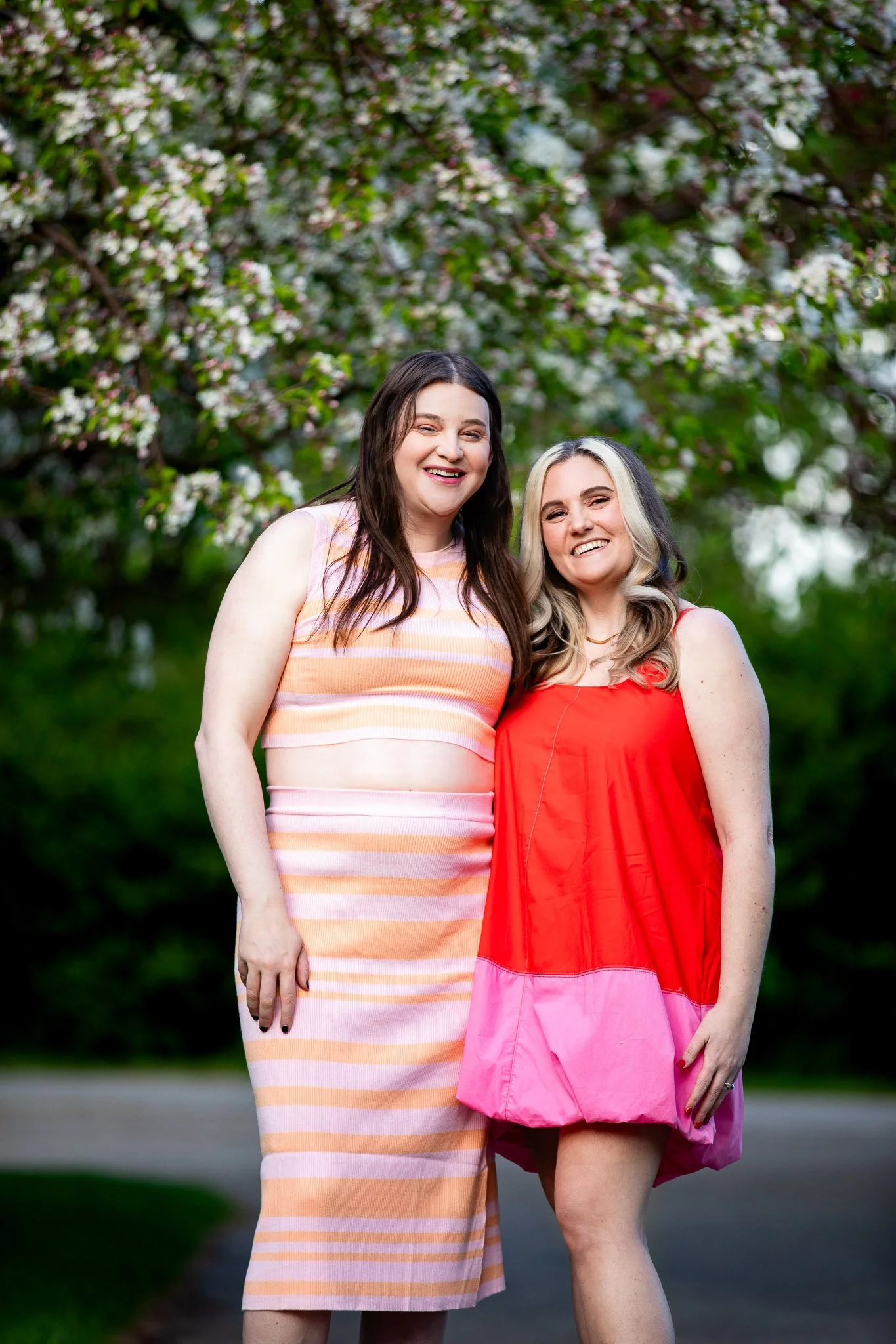 Dianna and Annika framed by blooming lilacs and colourful spring foliage during their Calgary engagement photos.