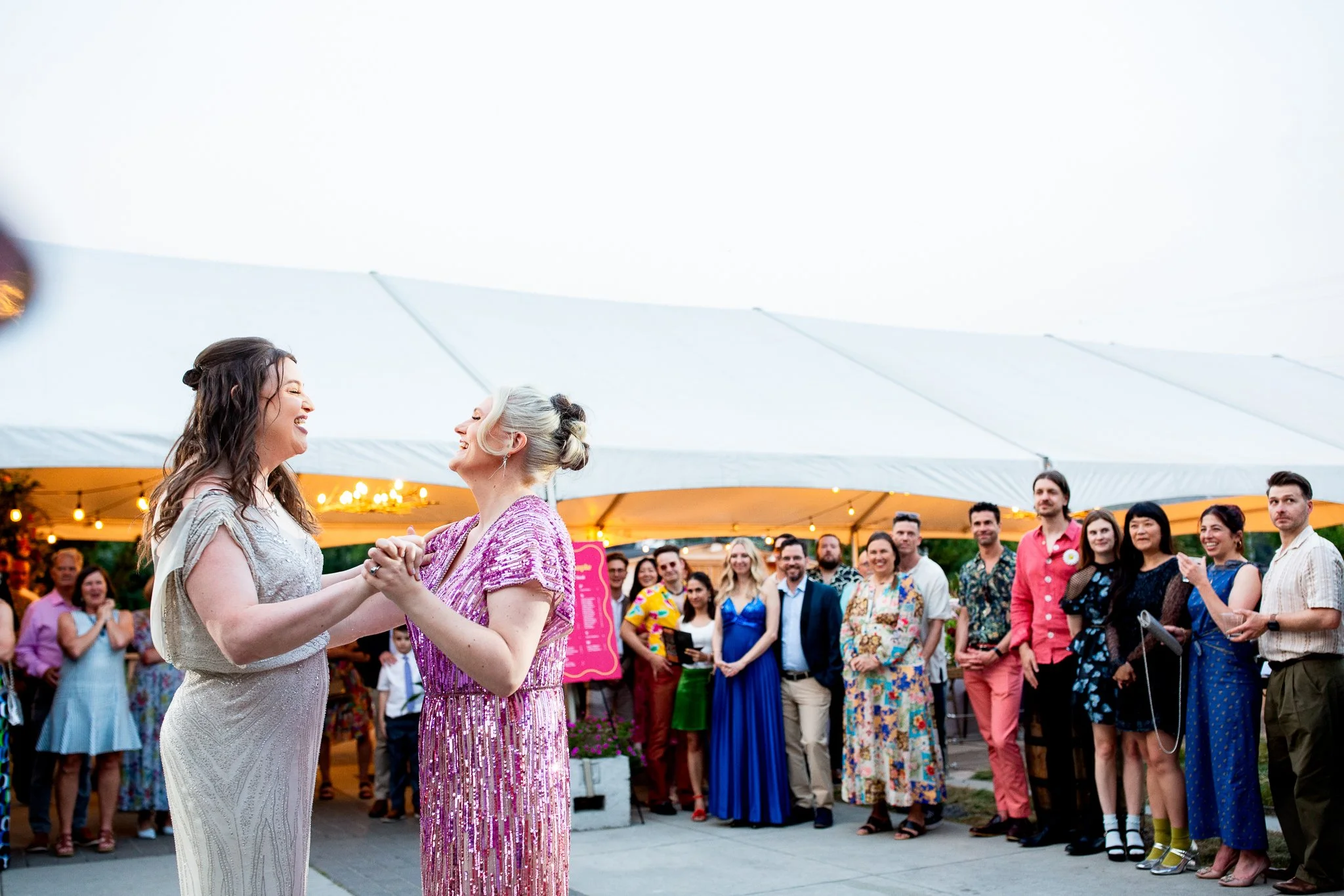 The newlyweds share a joyful first dance with friends and family on Deane House patio.