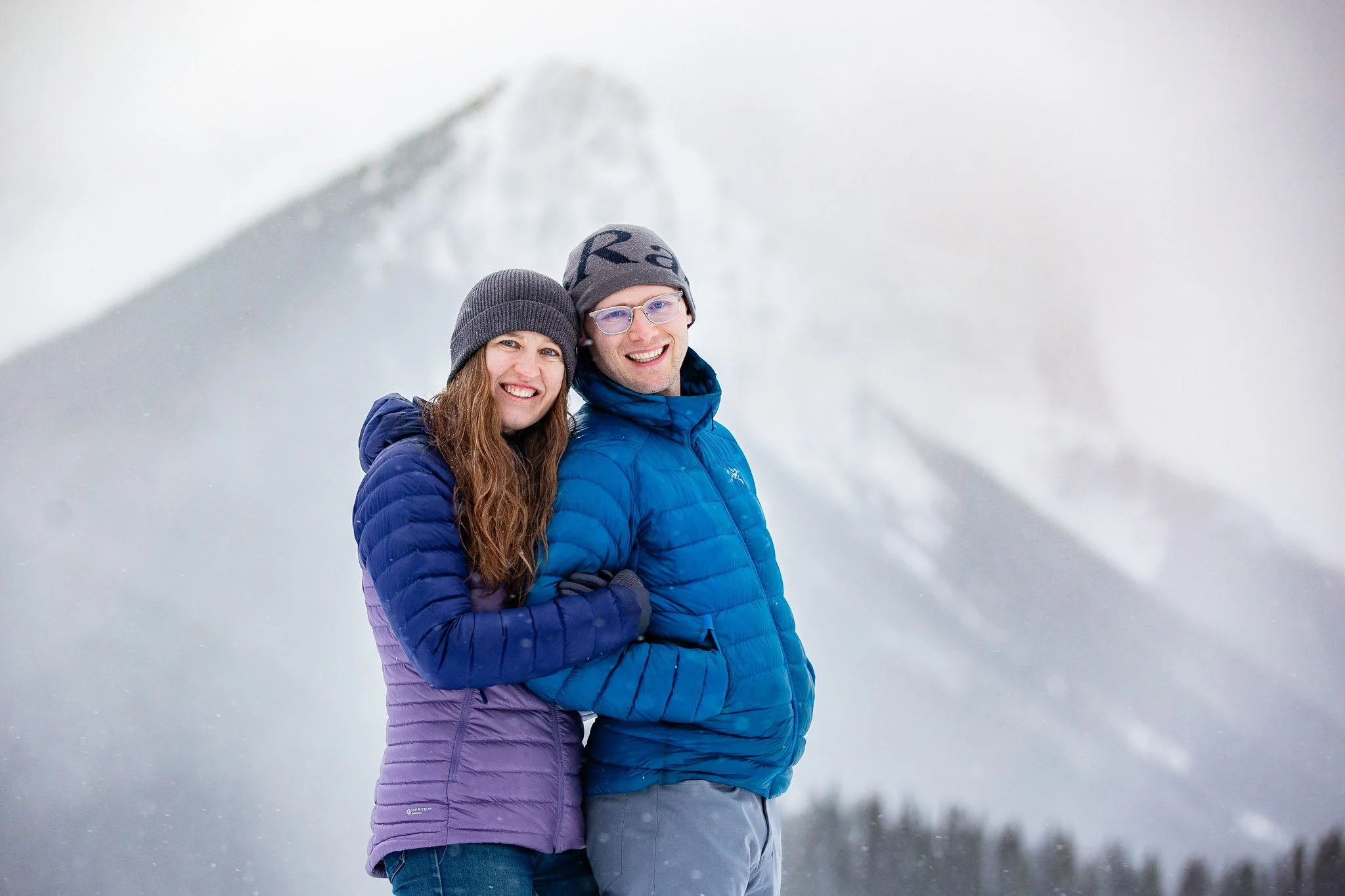 Tyler and Taryn smiling together in a snowy Alberta landscape during their winter engagement portraits.