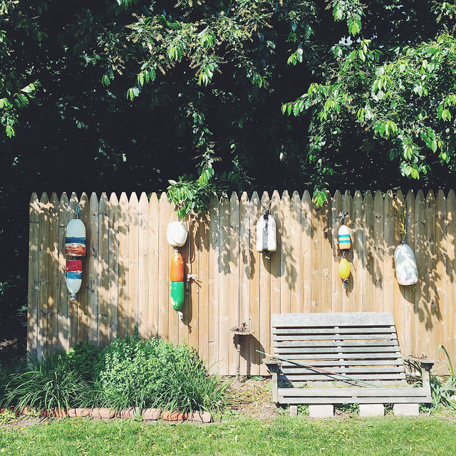 Painted buoys line a picket fence. 