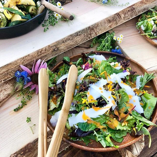 Our green salad with local greens, champagne heirloom tomato vinaigrette, pistachios, shavings of goat cheese Gouda and edible calendula flowers. All of the flowers we use to make our spreads pretty &amp; whimsical are edible. Captured here is calend