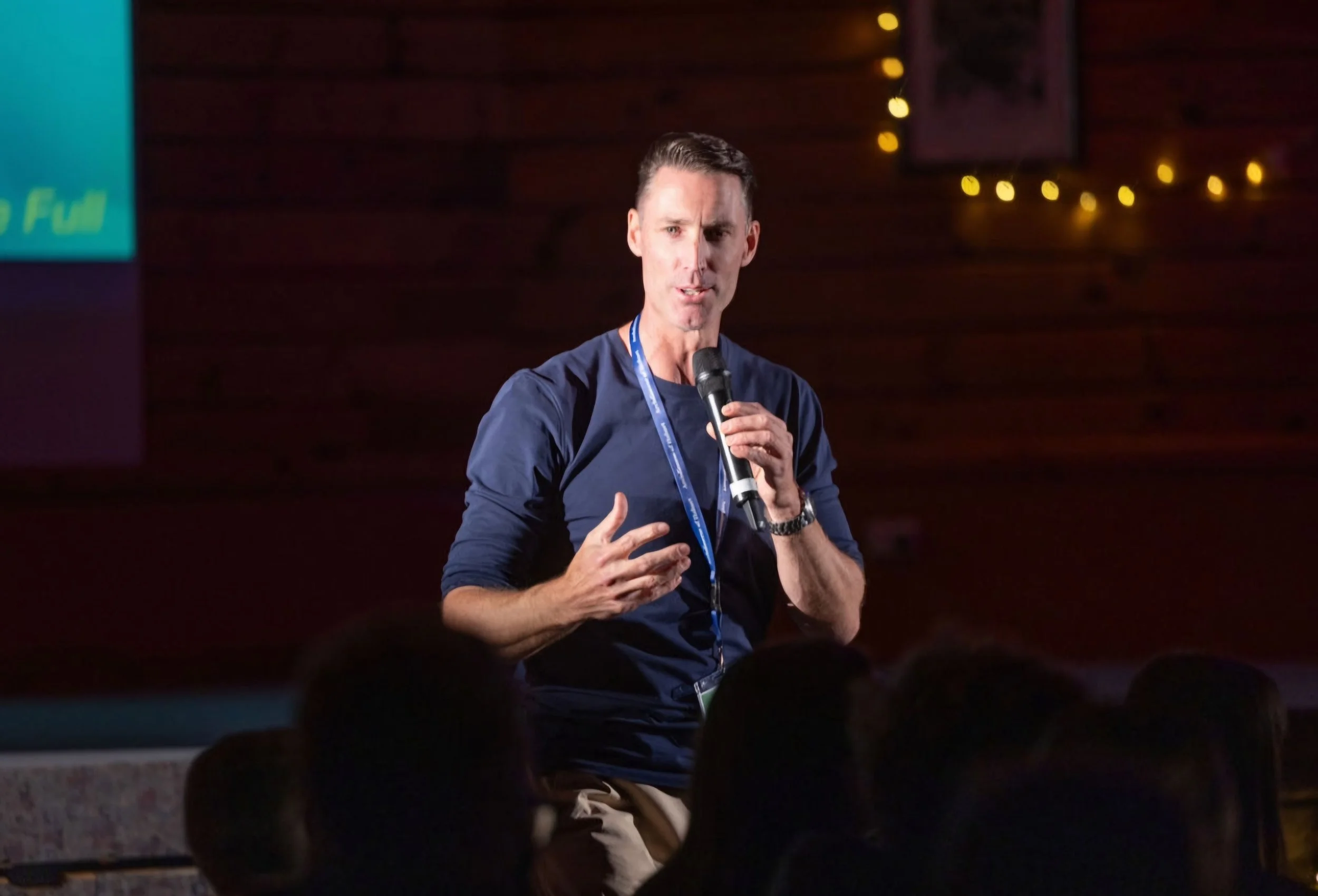 Sam Clear holding a microphone giving a talk at a conference or event with an audience watching.