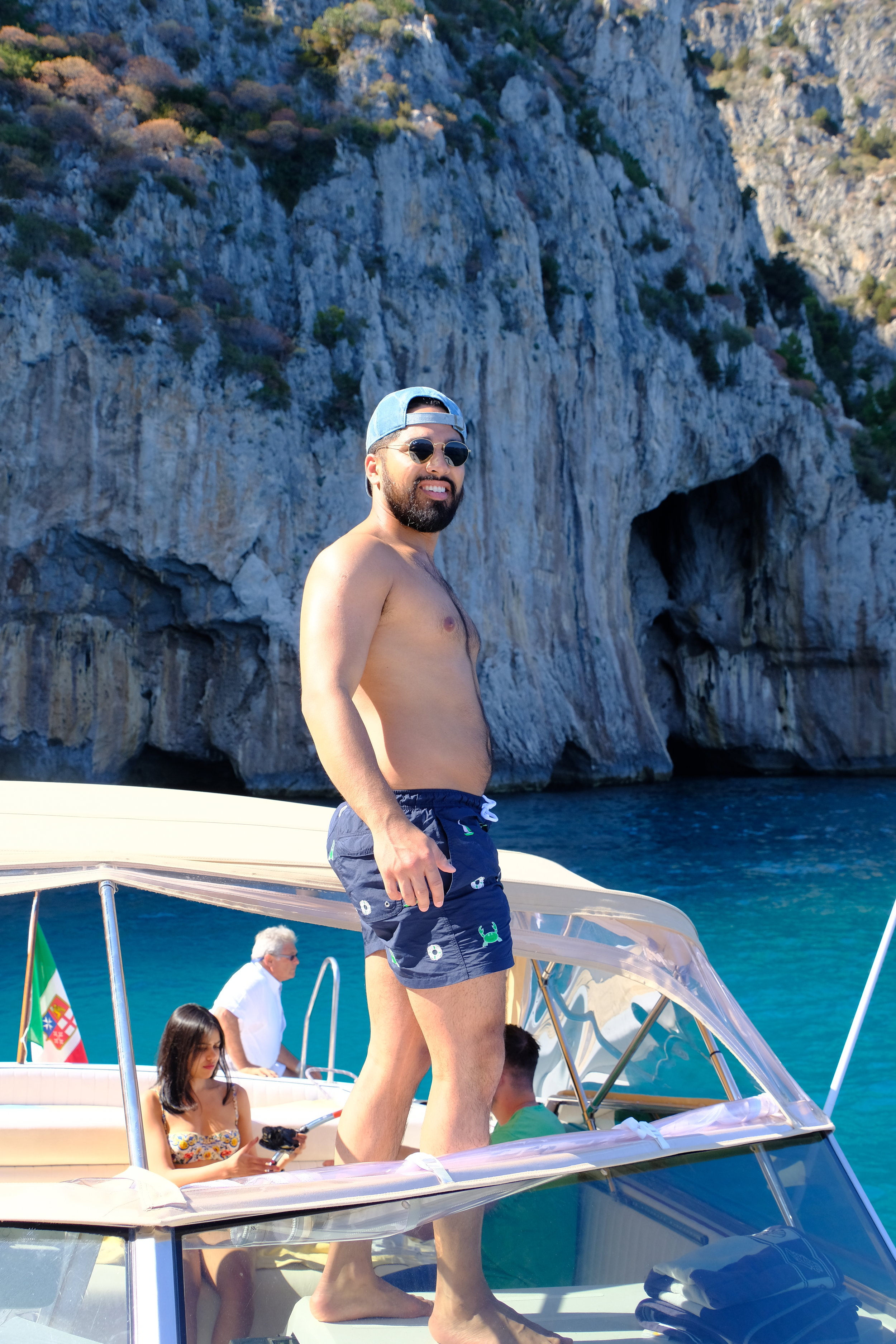 Swimming trunks by Thom Browne, sunglasses by Ray-Ban.