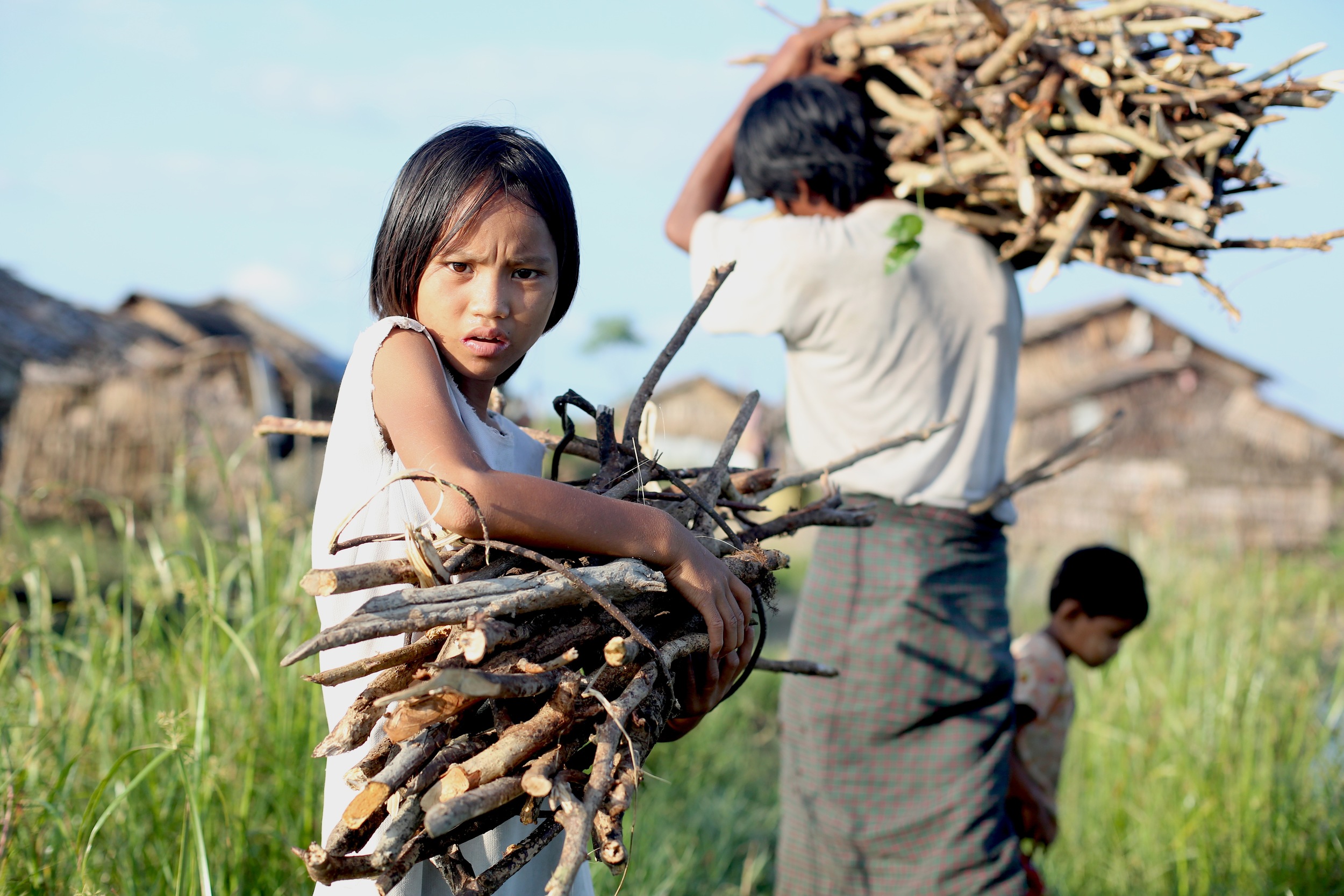 A girl in Myanmar collects wood with her family