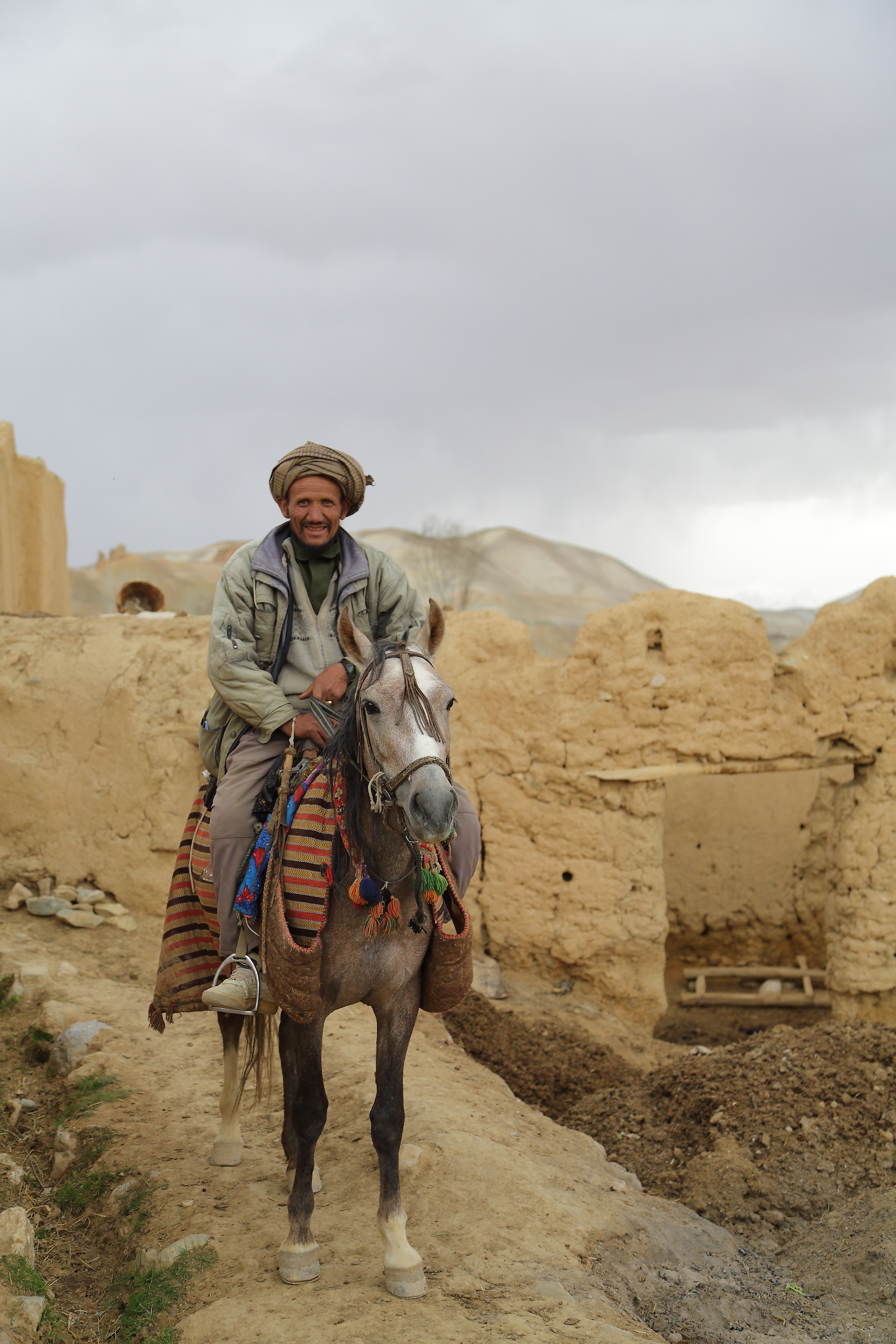 An Afghan man rides his horse through his village