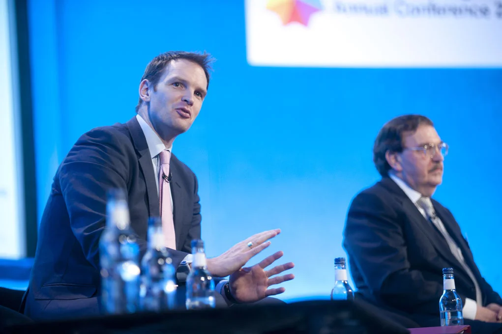 Portrait of a man speaking at a podium at a conference in London