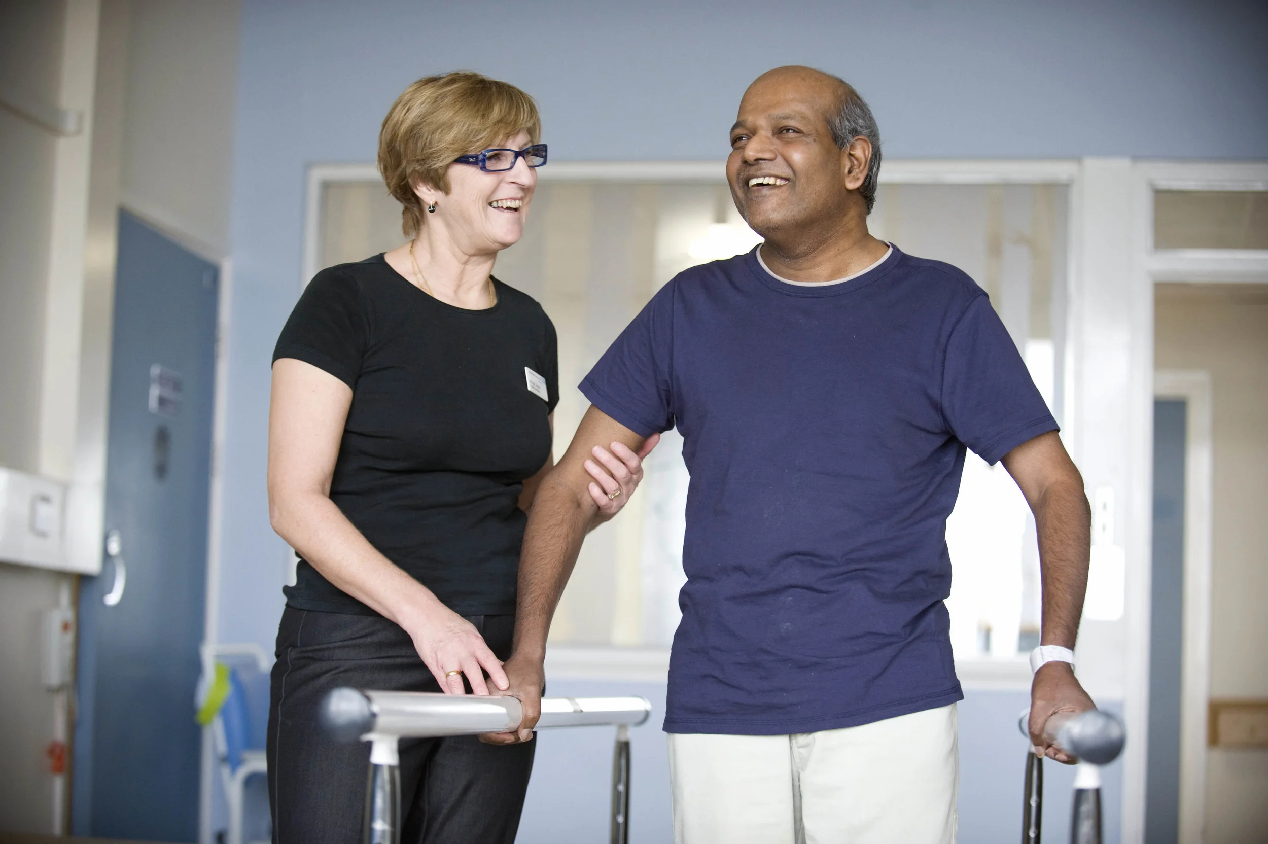 A medical professional helping a patient to walk using bars in rehabilitation