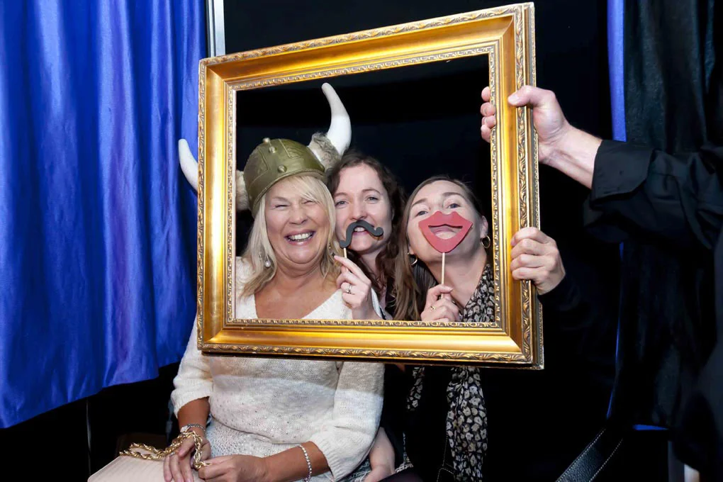 Three women laughing at a drinks reception looking to camera