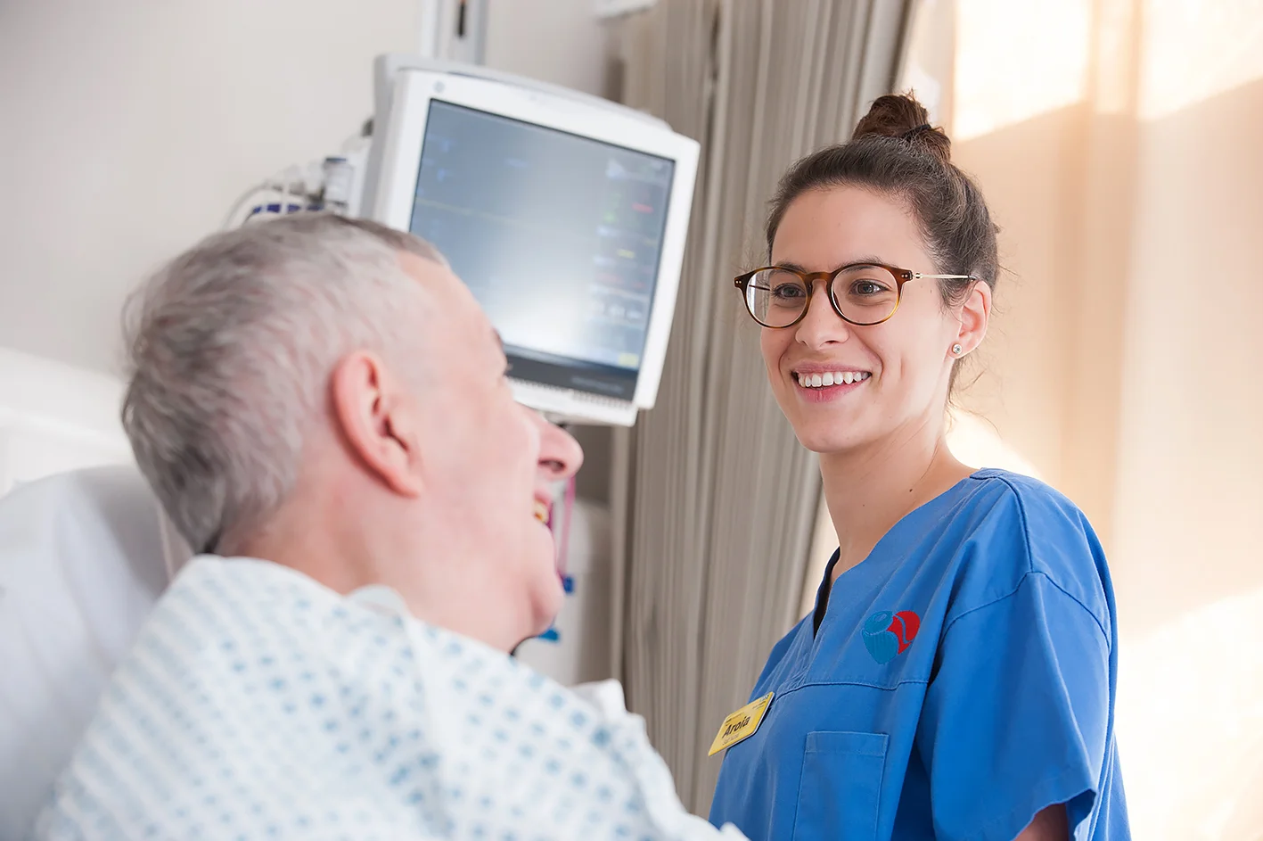 Portrait of Nurse smiling looking at a patient in a hospital bed