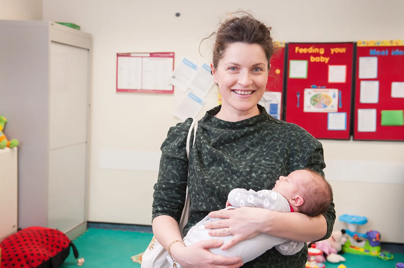 A portrait of a mother with a baby smiling looking to camera