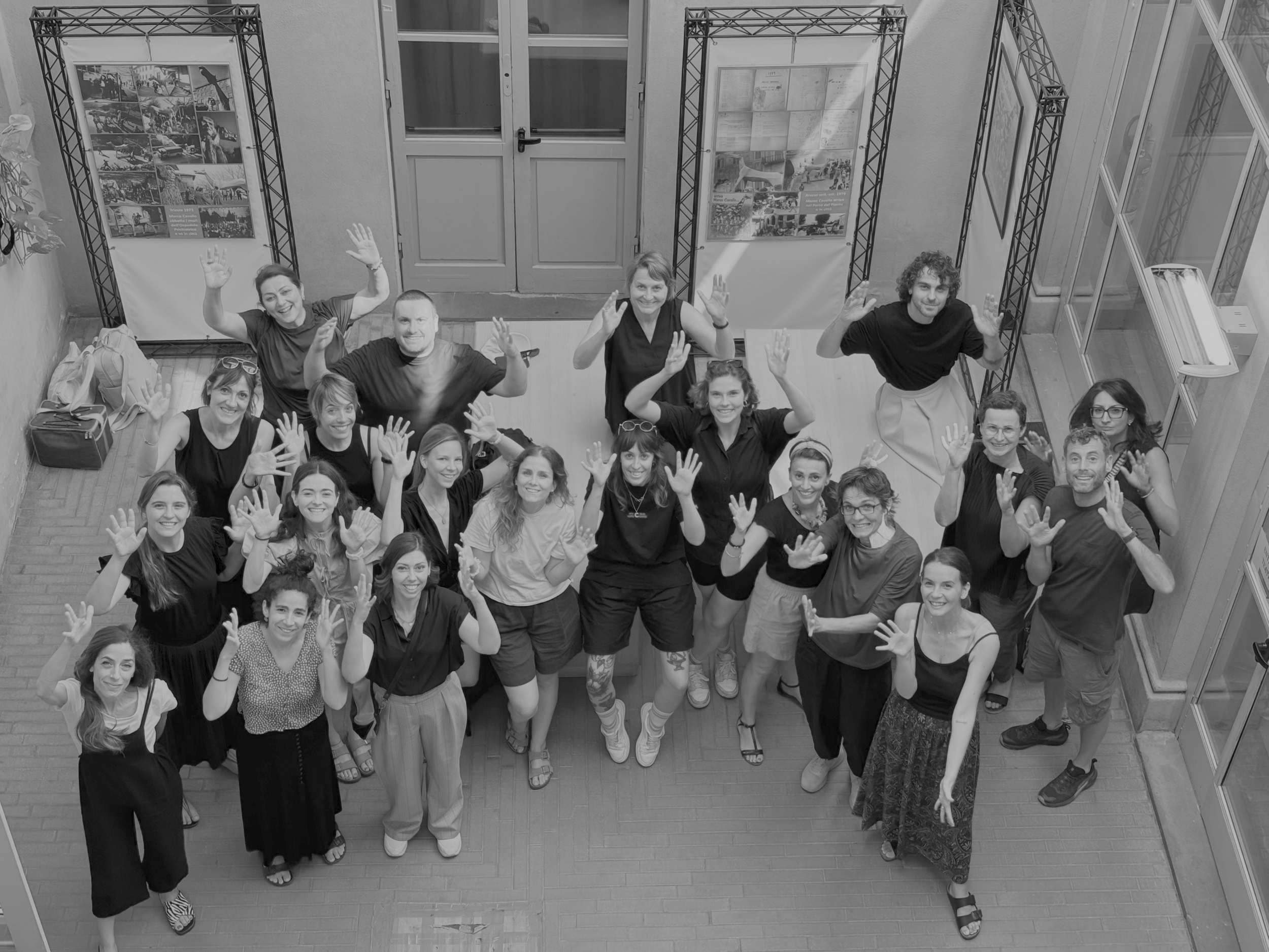 Students standing all together and looking up and waving to the photographer who is one floor above