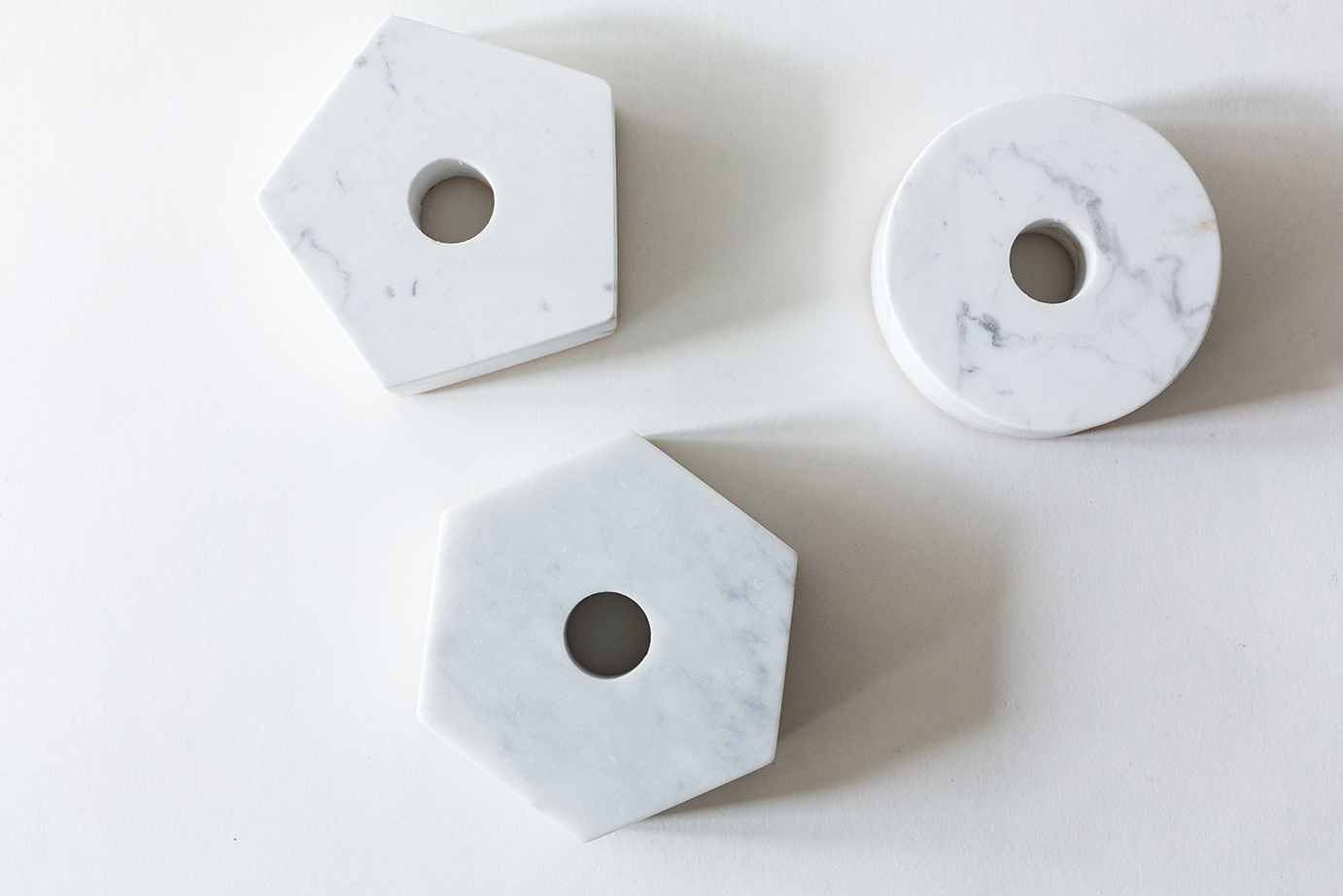 White Carrara Stone Candle Holders in round, triangle and hexagon shapes on white background.