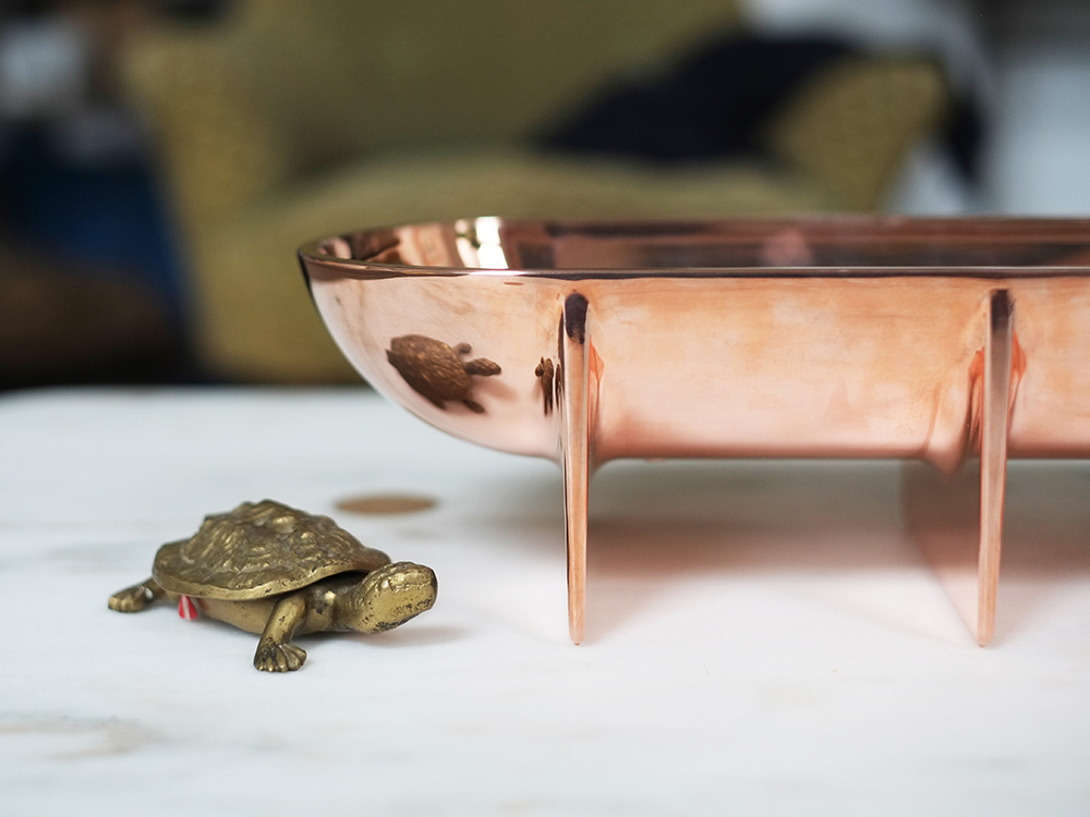 Large Copper Standing Bowl styled on a white marble coffee table with brass accessories
