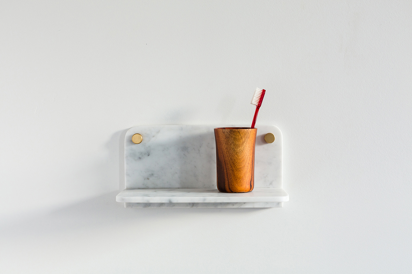 White Carrara Marble Stone Shelf holding a wooden cup and toothbrush on a white background