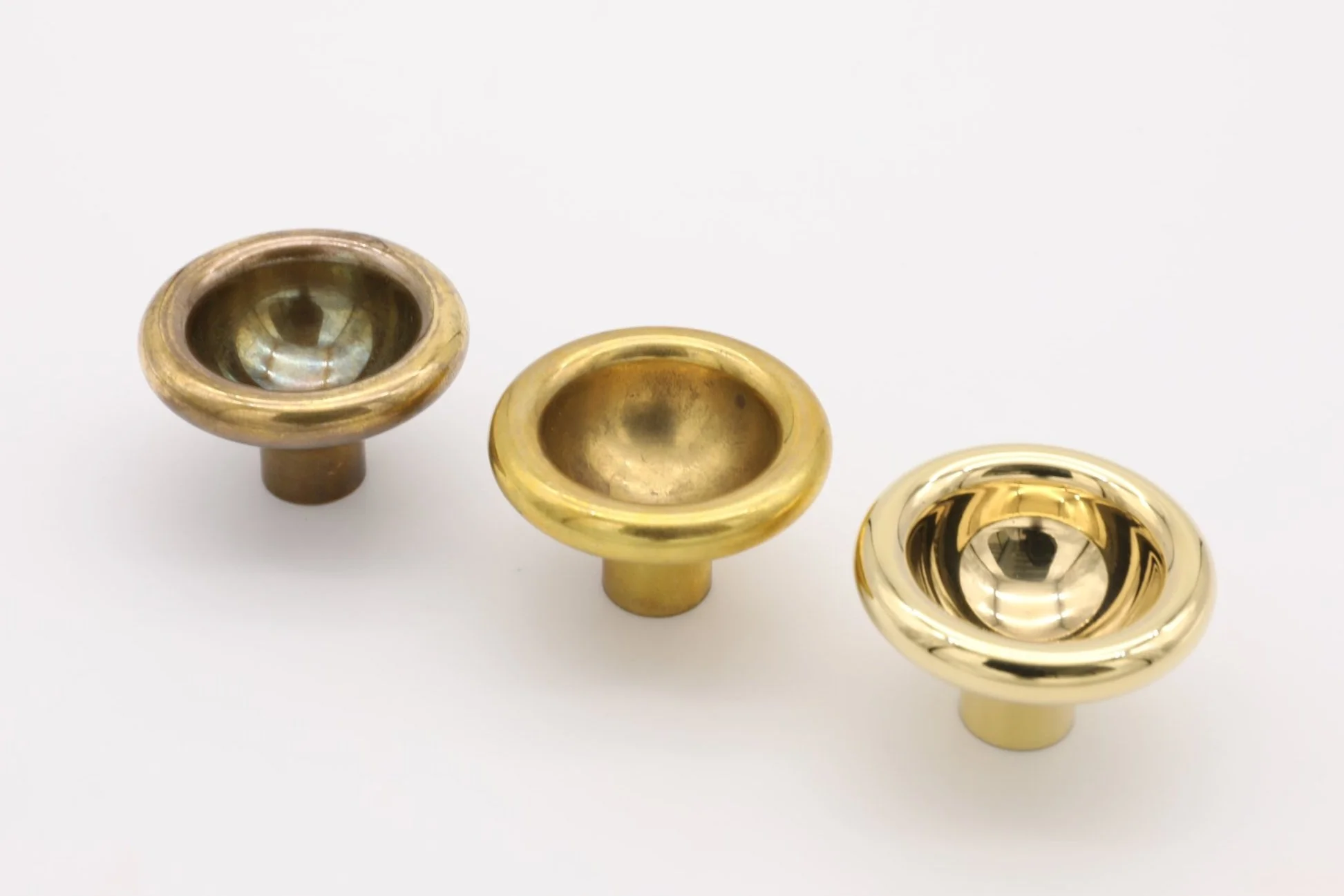 Image shows different stages of patina on Brass Concave Knobs: Highly Polished, Light Patina, Deep Patina