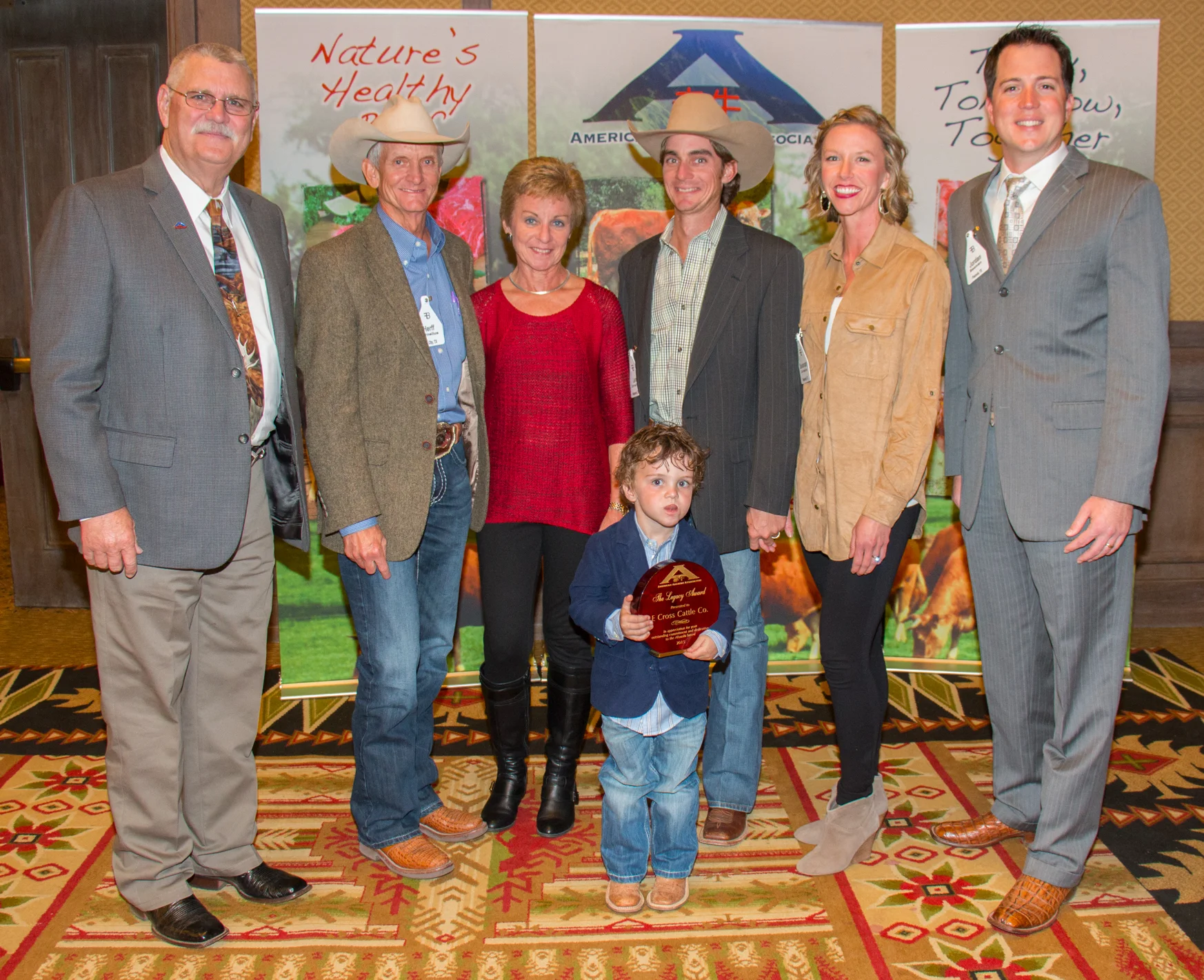 Bubba Bain, Executive Director American Akaushi Association with E Cross Cattle Company the 2015 Legacy Award Winner; Herff and Nancy Cornelius, Len and Savannah Cornelius, Jordan Beeman, President HeartBrand Beef, Inc., in front holding the award is Wyatt Cornelius, son of Len and Savannah.