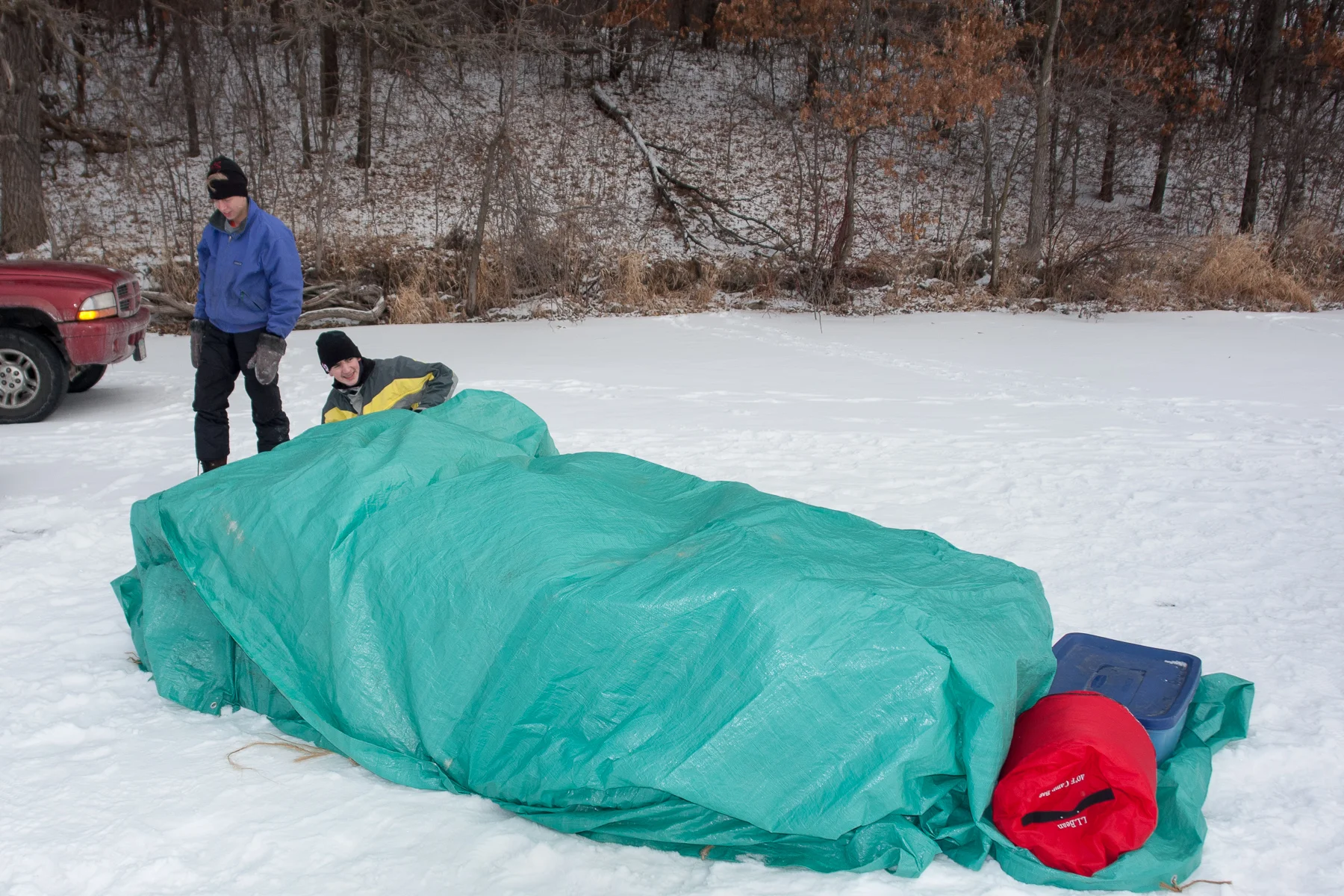 Erik J and Erik C improvise a shelter using their sled and a tarp for wilderness survival exercises at White Pass.