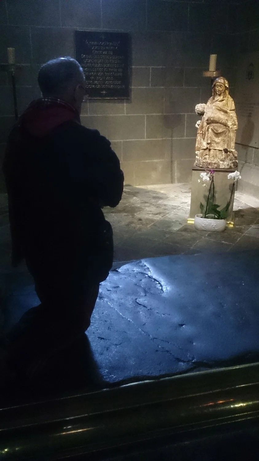 At prayer before the statue and kneeling on the ancient 'fever rock'.