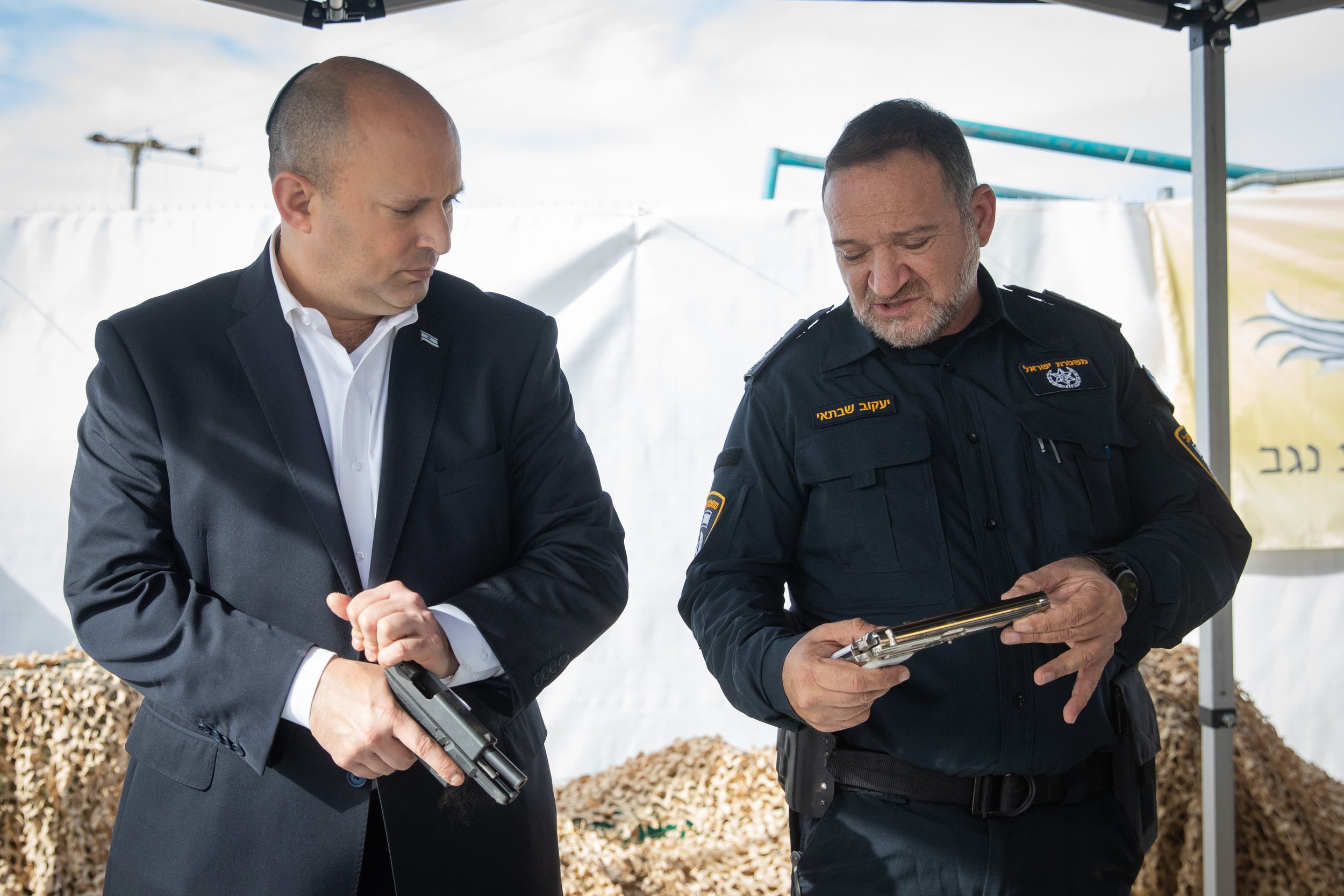  Israeli Prime Minister Naftali Bennett and Chief of Police Kobi Shabta looking at seized guns during a visit in Rahat, southern Israel, December 6, 2021 