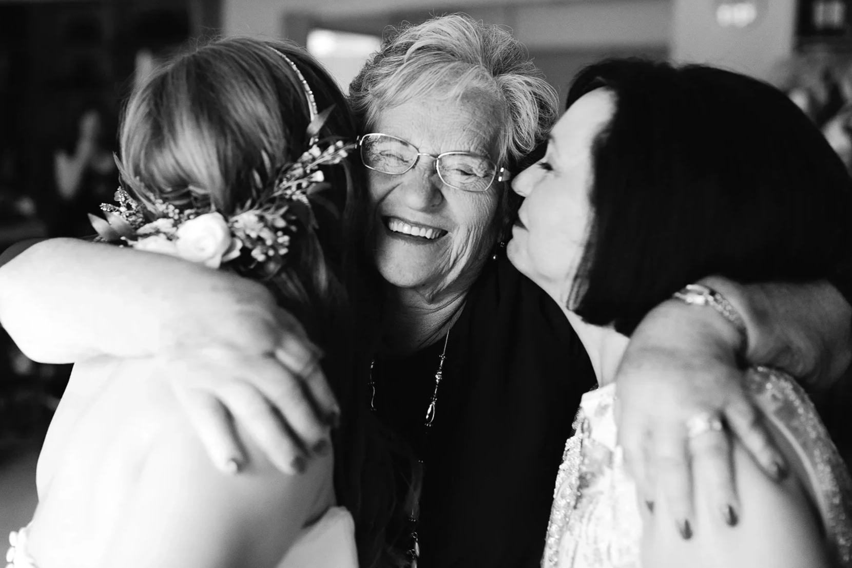 Emotional candid wedding photo of family hugging older woman during wedding day