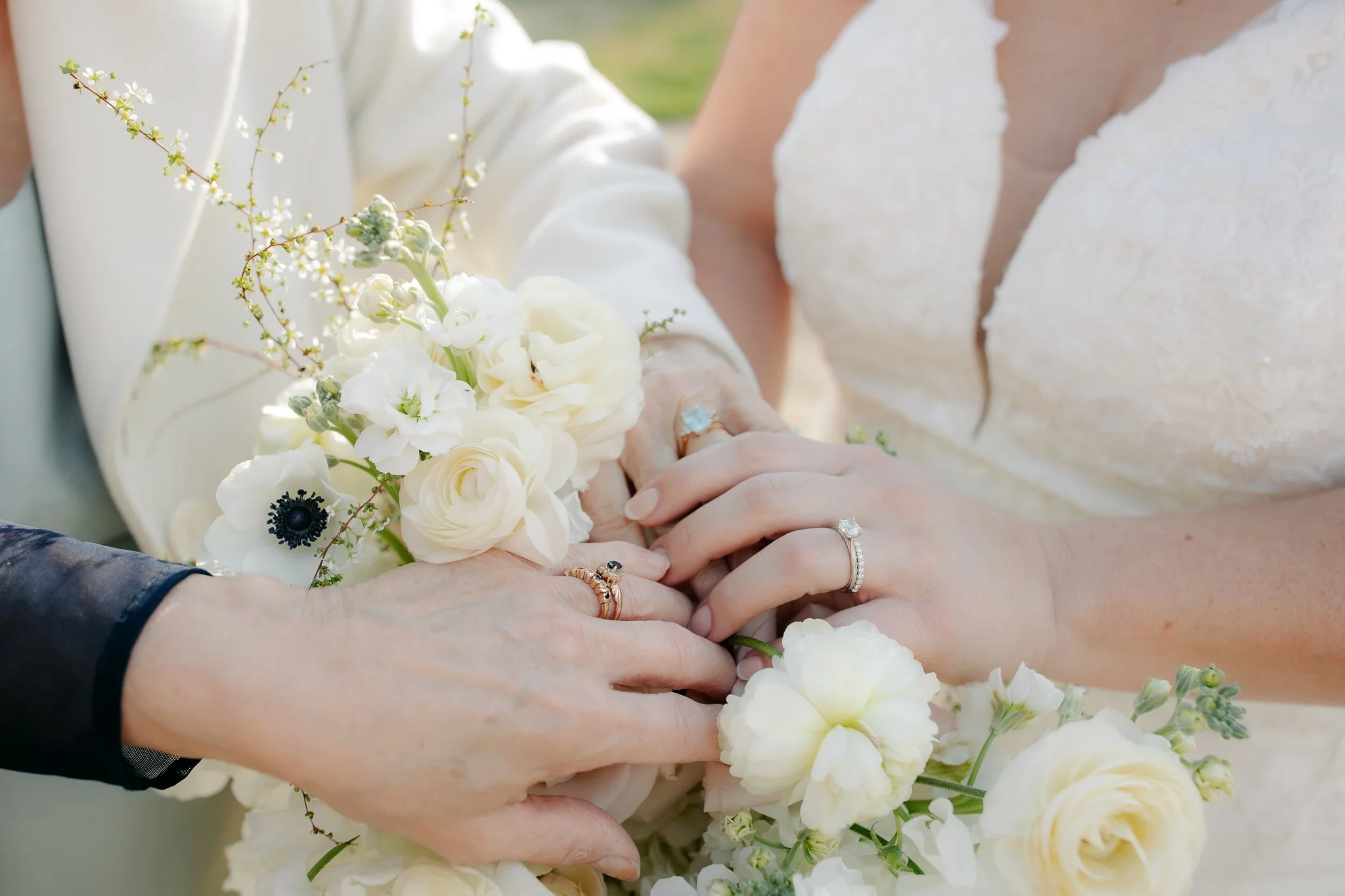 Close-up of couple’s hands with wedding rings and bouquet
