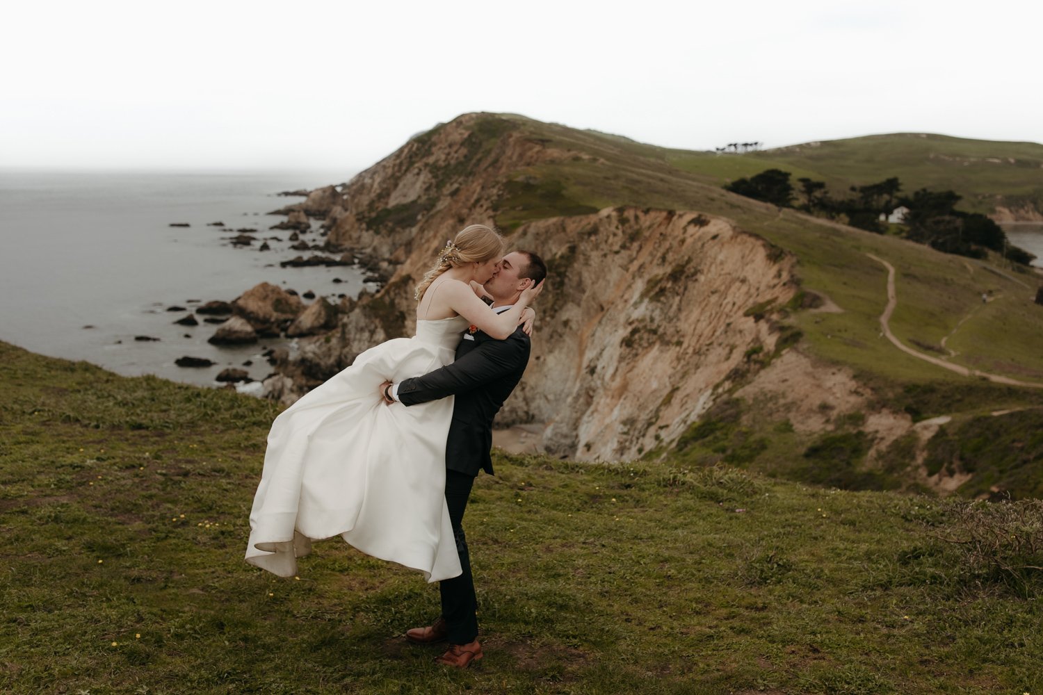 Couple embracing on coastal cliffs at Point Reyes National Seashore elopement