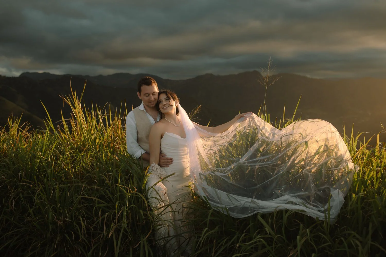 Bride and groom surrounded by golden light as the veil moves in the wind during a mountain elopement