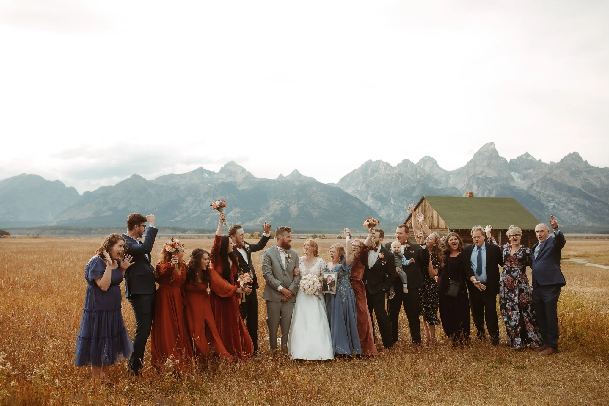 Wedding party celebrating together in a field with the Teton mountains in the background