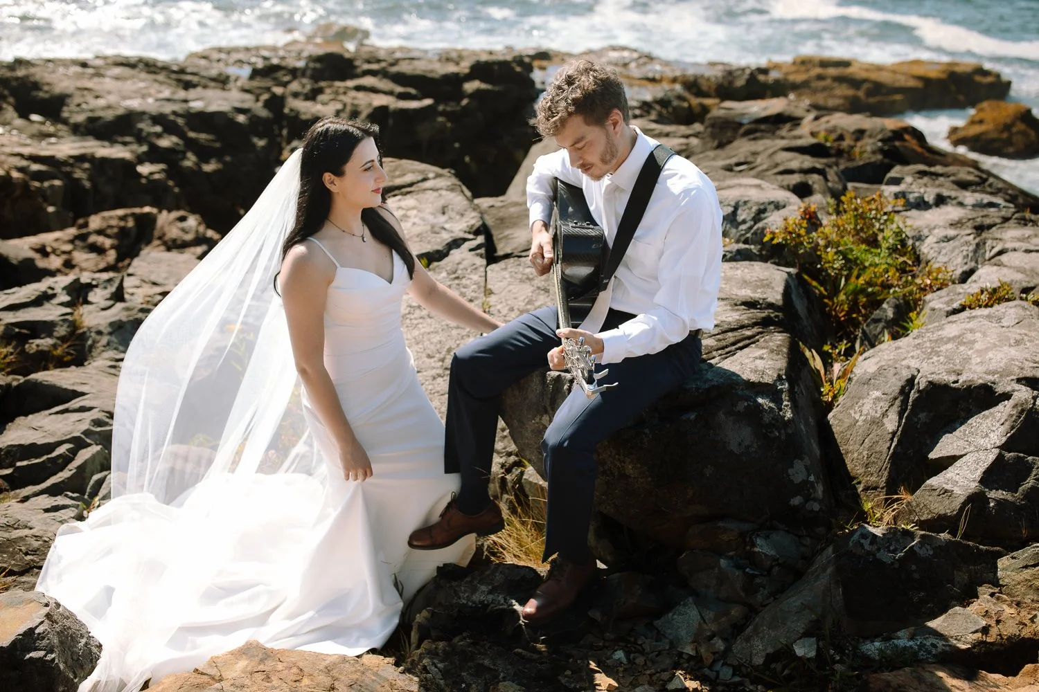 Bride and groom sharing a quiet musical moment on the rocky coast during their Acadia elopement