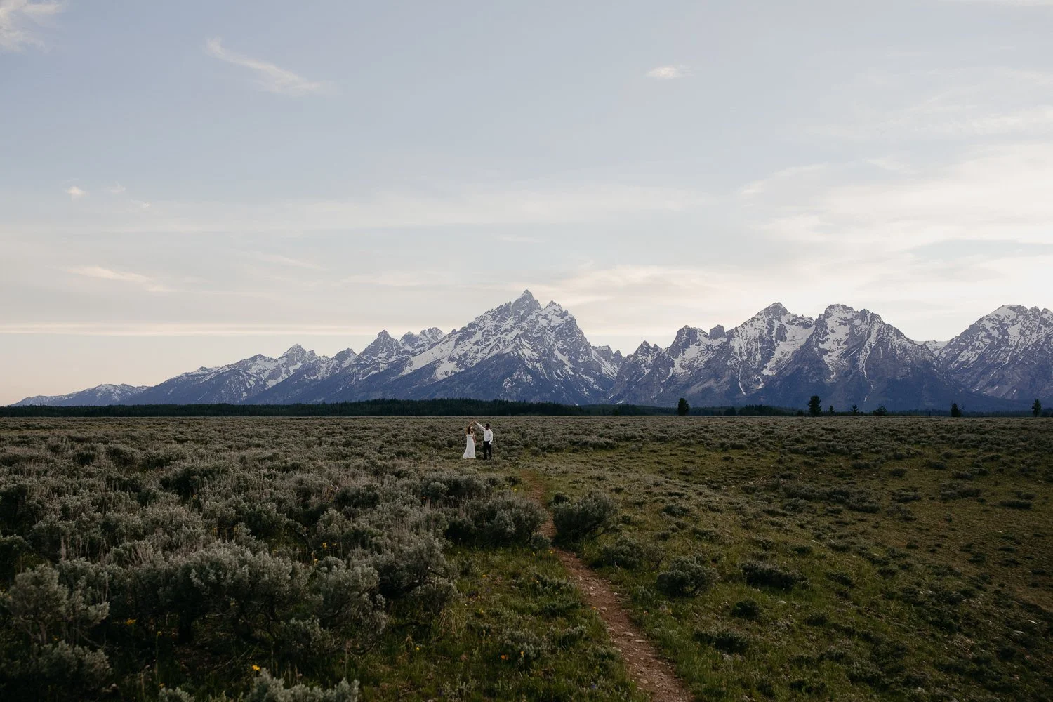 Wide engagement photo of couple in the landscape of Grand Teton National Park