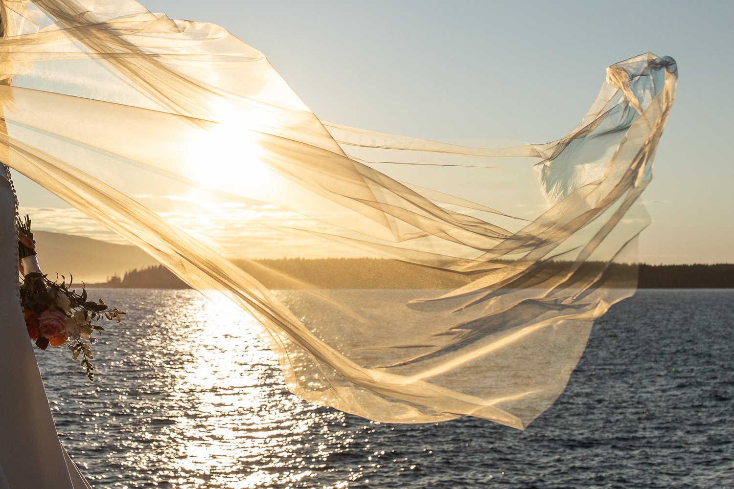 Bride’s veil lifting in the coastal breeze over the ocean during a sunset elopement in Acadia National Park