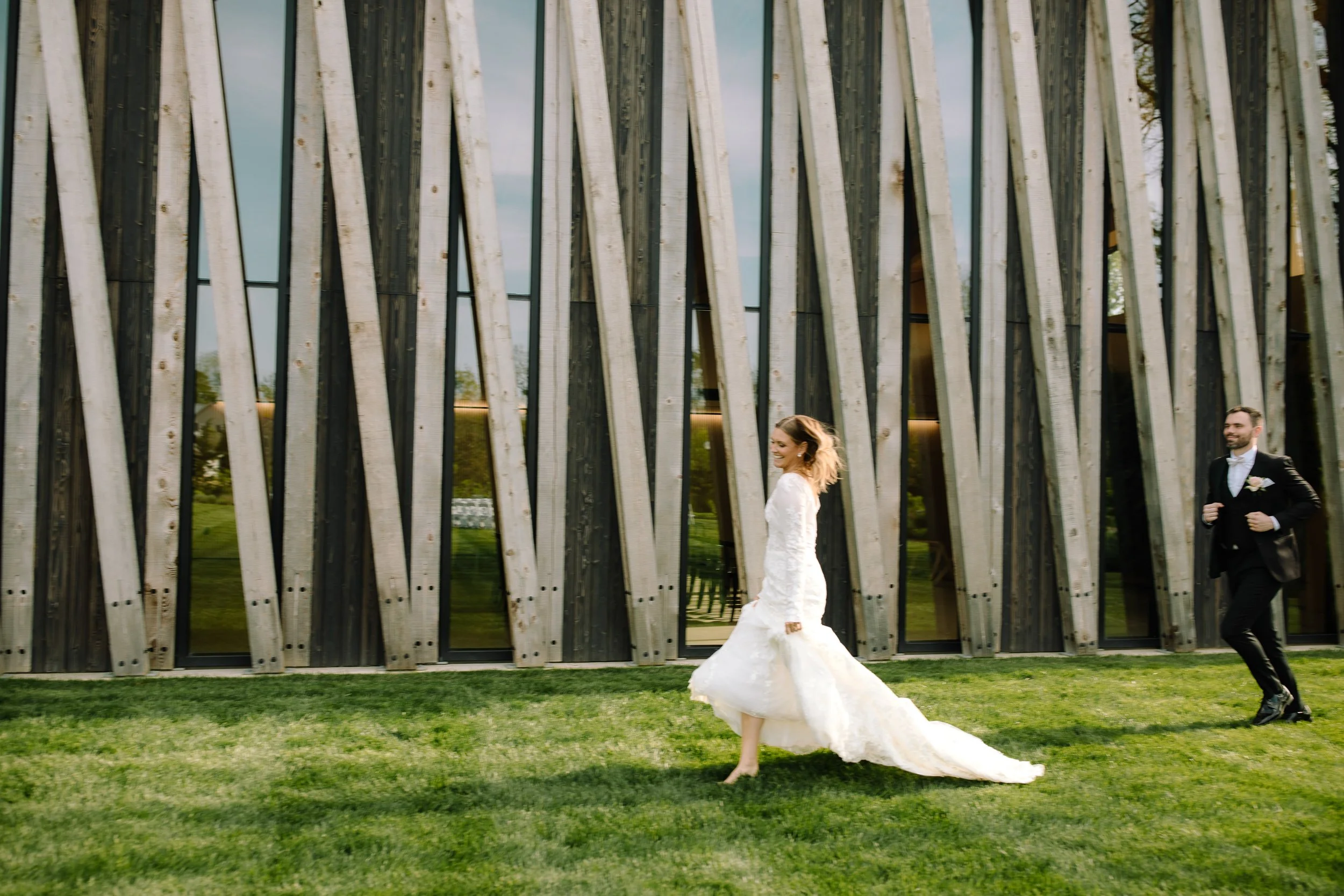 Bride smiling as the groom walks toward her outside the Arboretum building at Jorgensen Farm The Gardens.