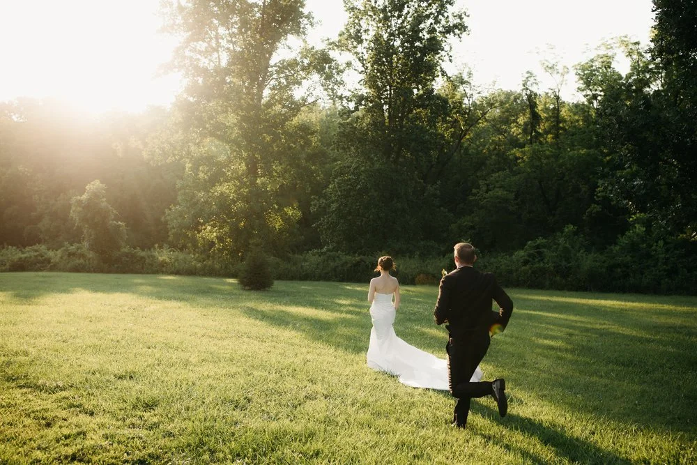 Cincinnati wedding photographer captures a couple running through the grass at sunset at The French House