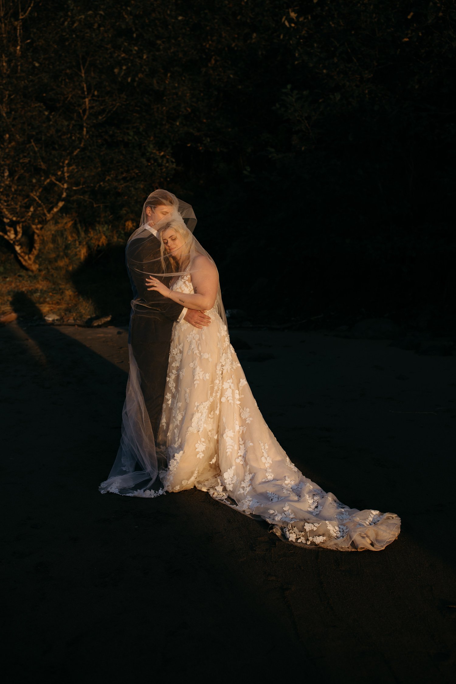 Artistic black and white portrait of bride under veil at sunset