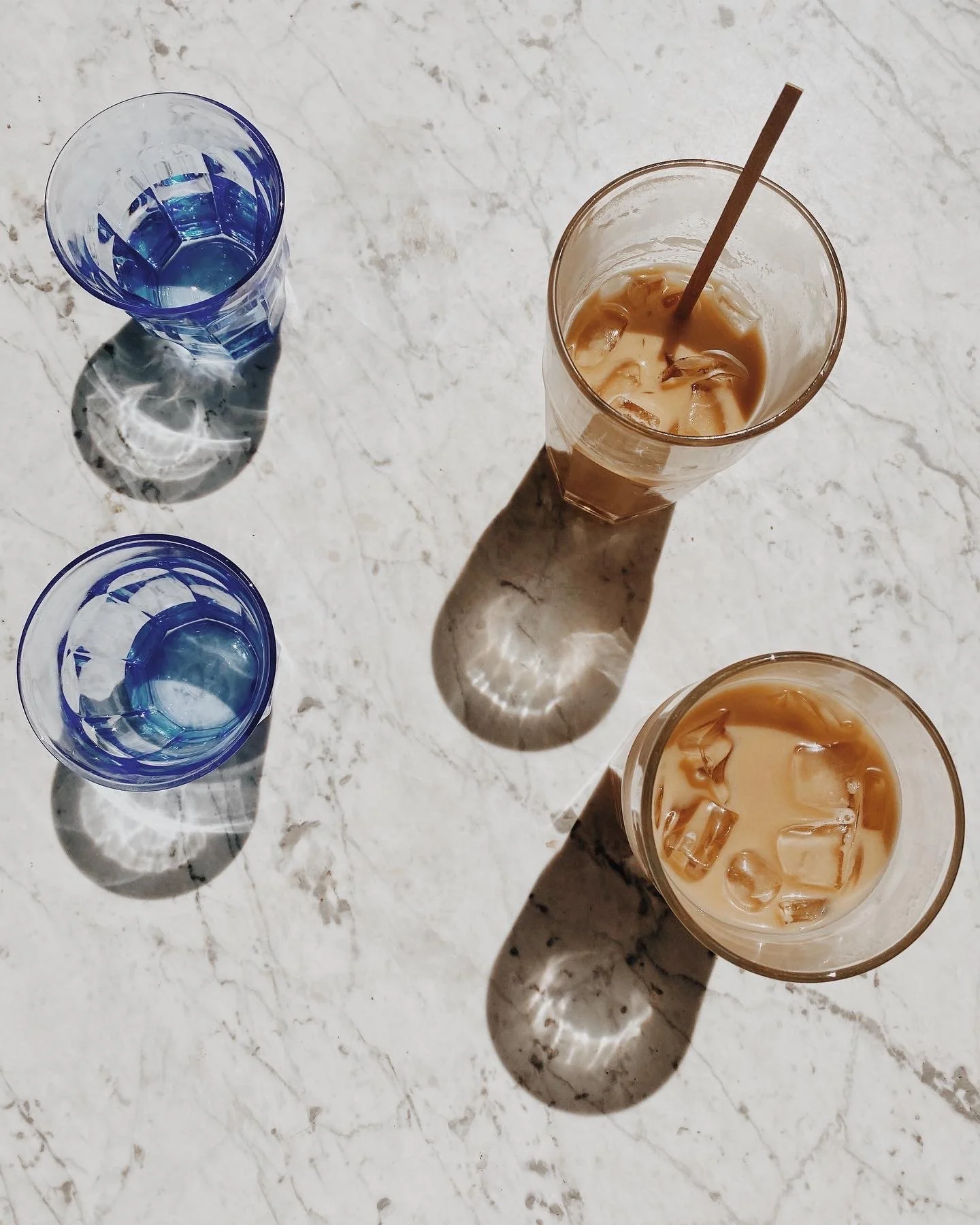 Iced coffee drinks and blue glassware on a marble café table in Jackson Hole