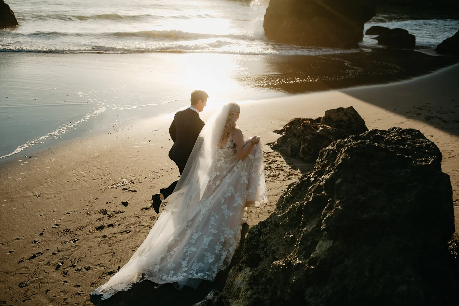 Couple walking between large sea stacks at College Cove during golden hour