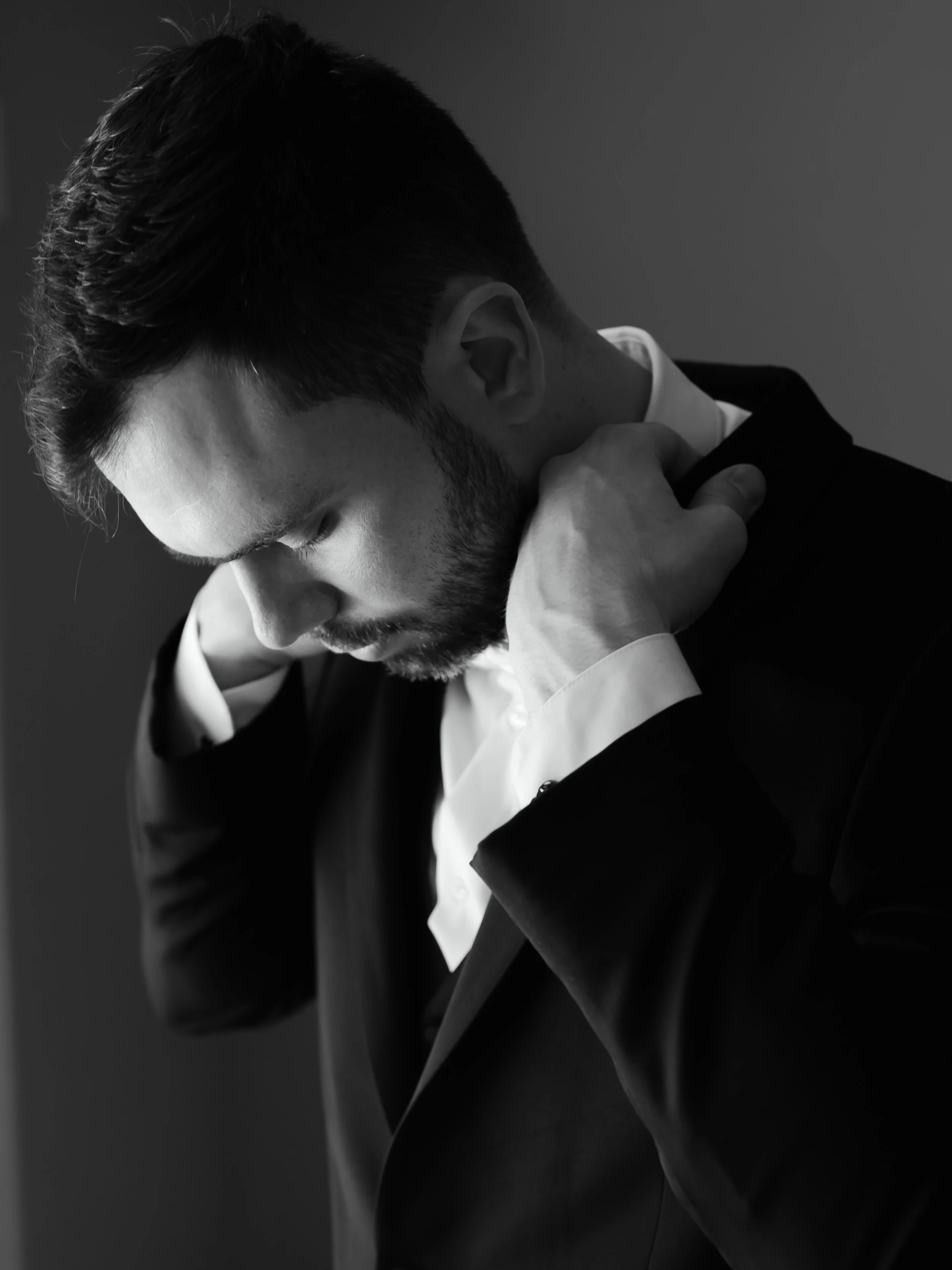 Black and white portrait of groom adjusting jacket before wedding in Columbus, Ohio