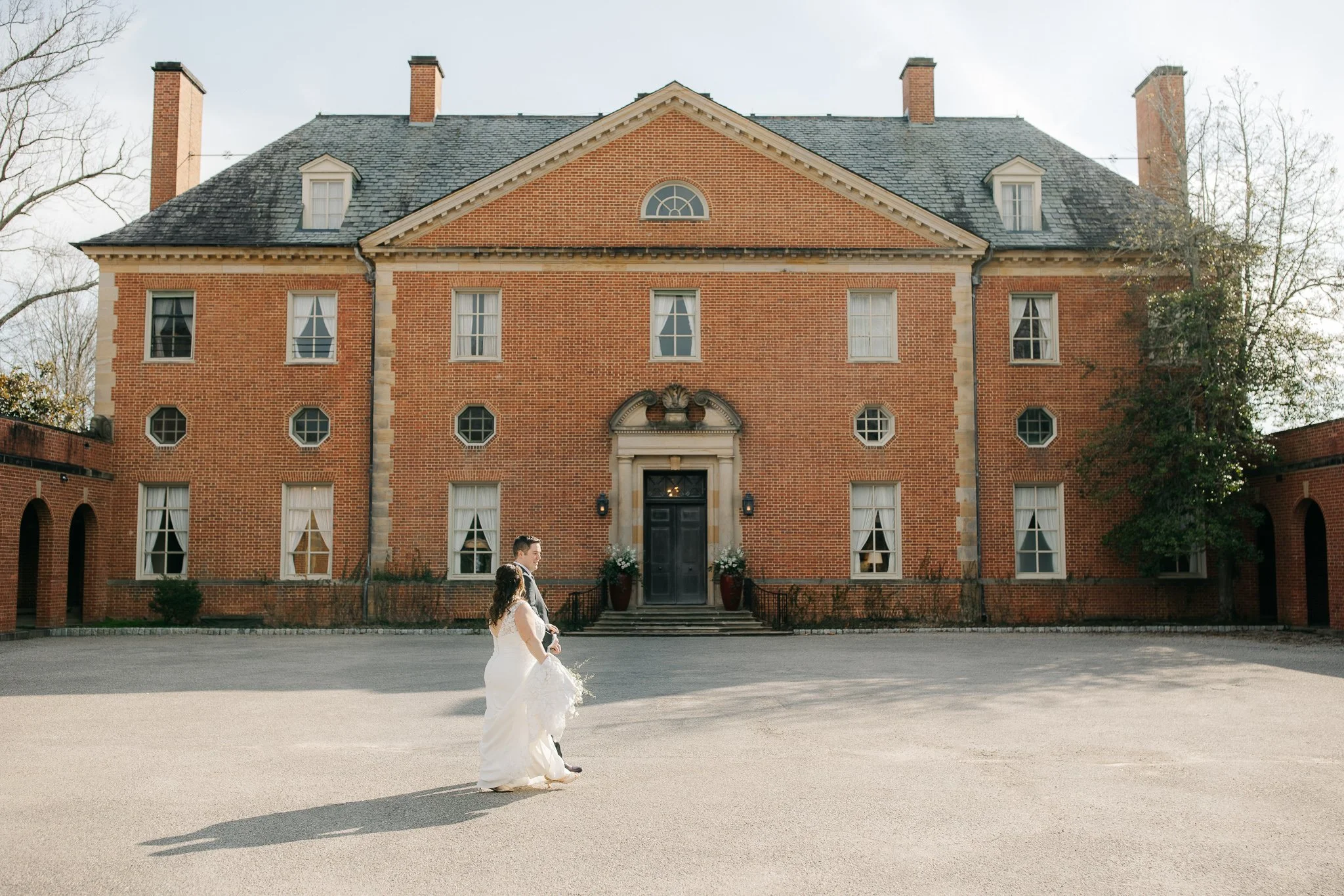 Bride and groom walking across courtyard in front of Peterloon Estate