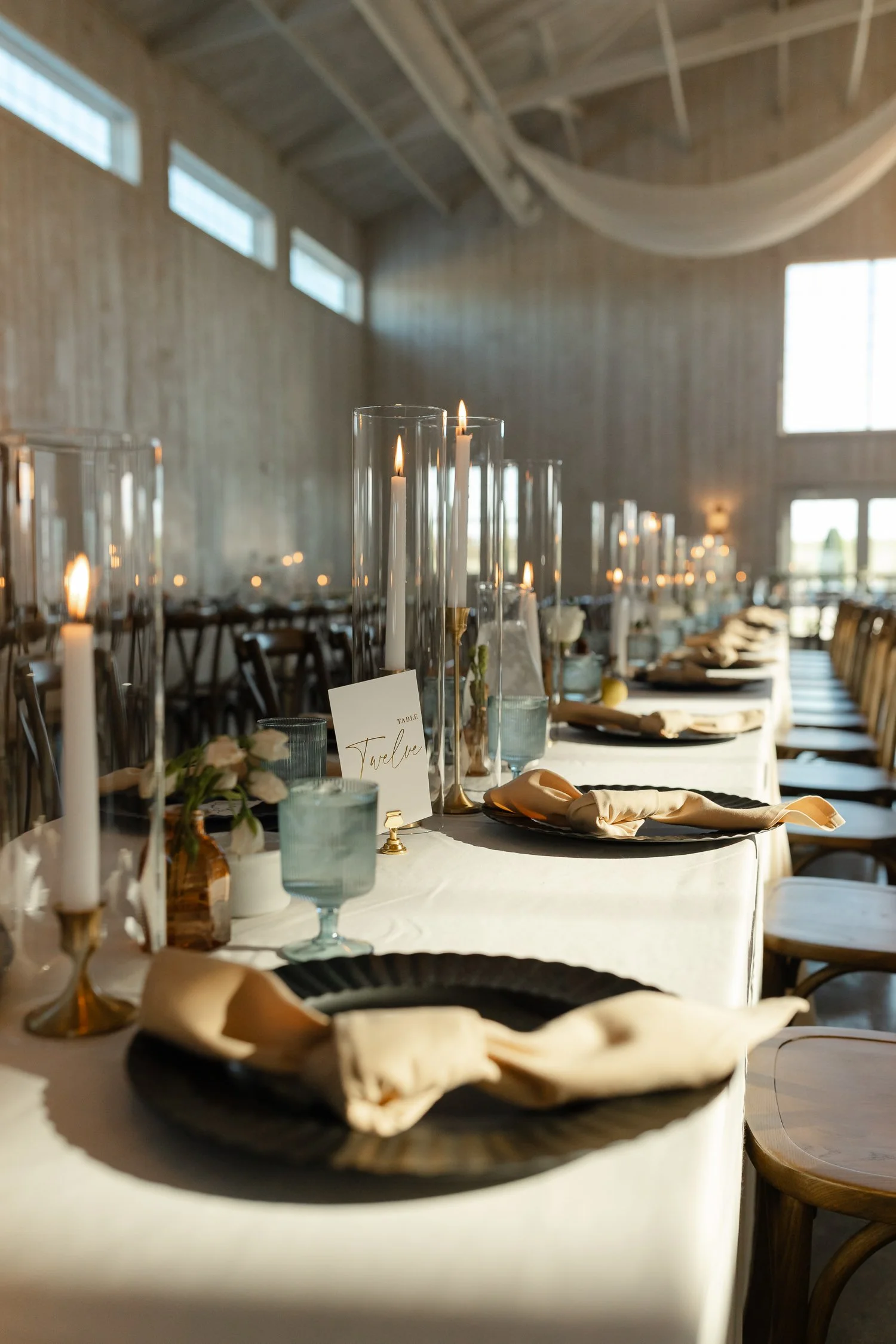 Long farmhouse-style reception tables with candles and place settings inside Ivory Meadows wedding venue in Dayton, Ohio