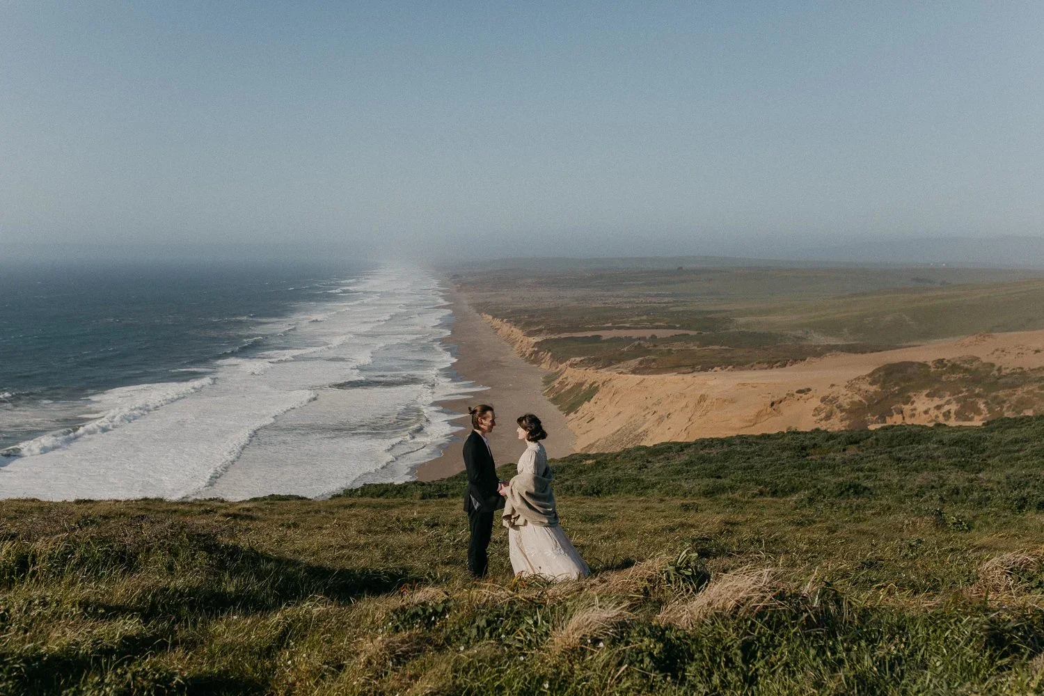 Couple standing above the coastline at Point Reyes National Seashore during elopement