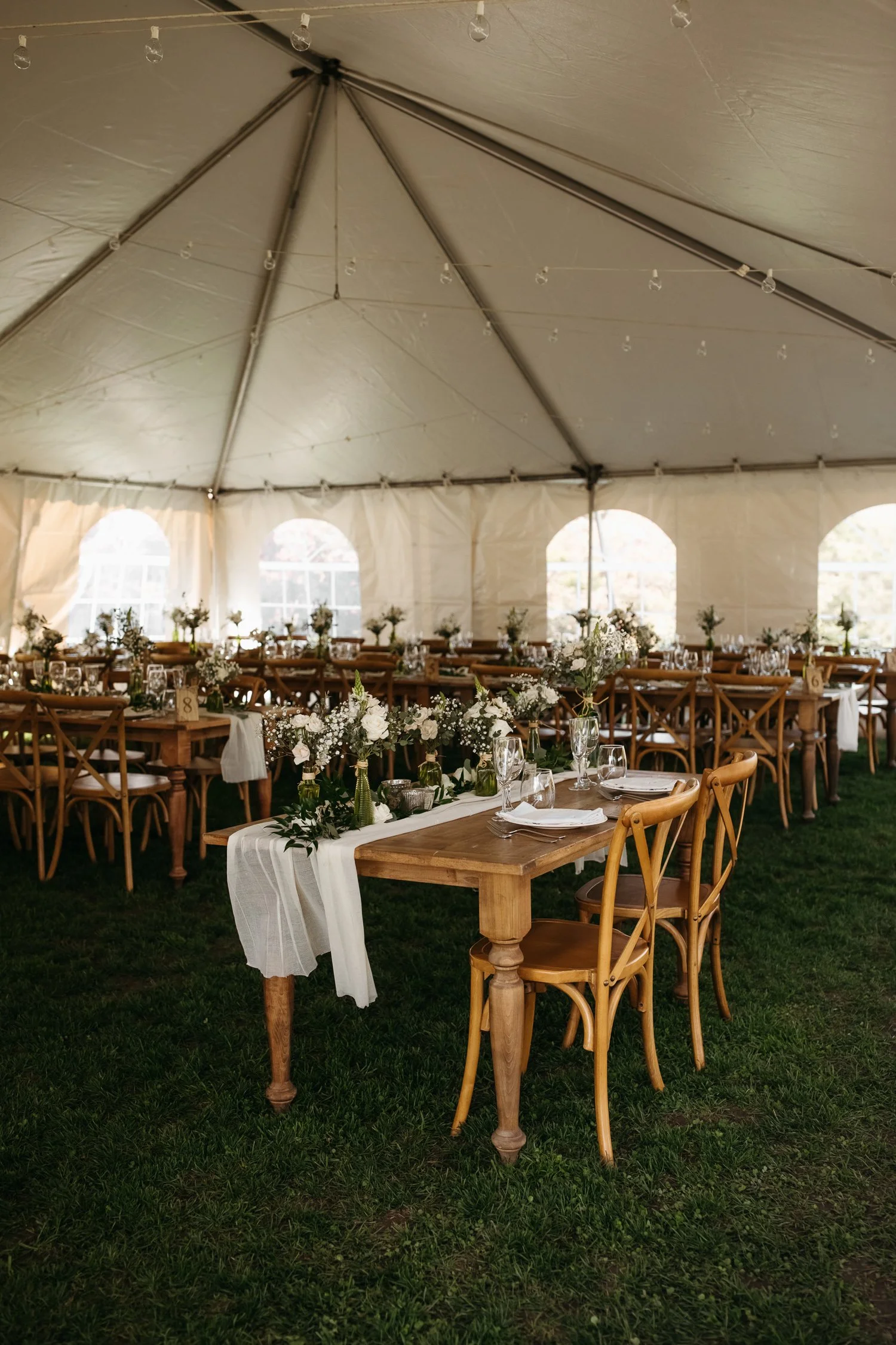 Outdoor tent reception setup at Windrift Hall with long farm tables and greenery