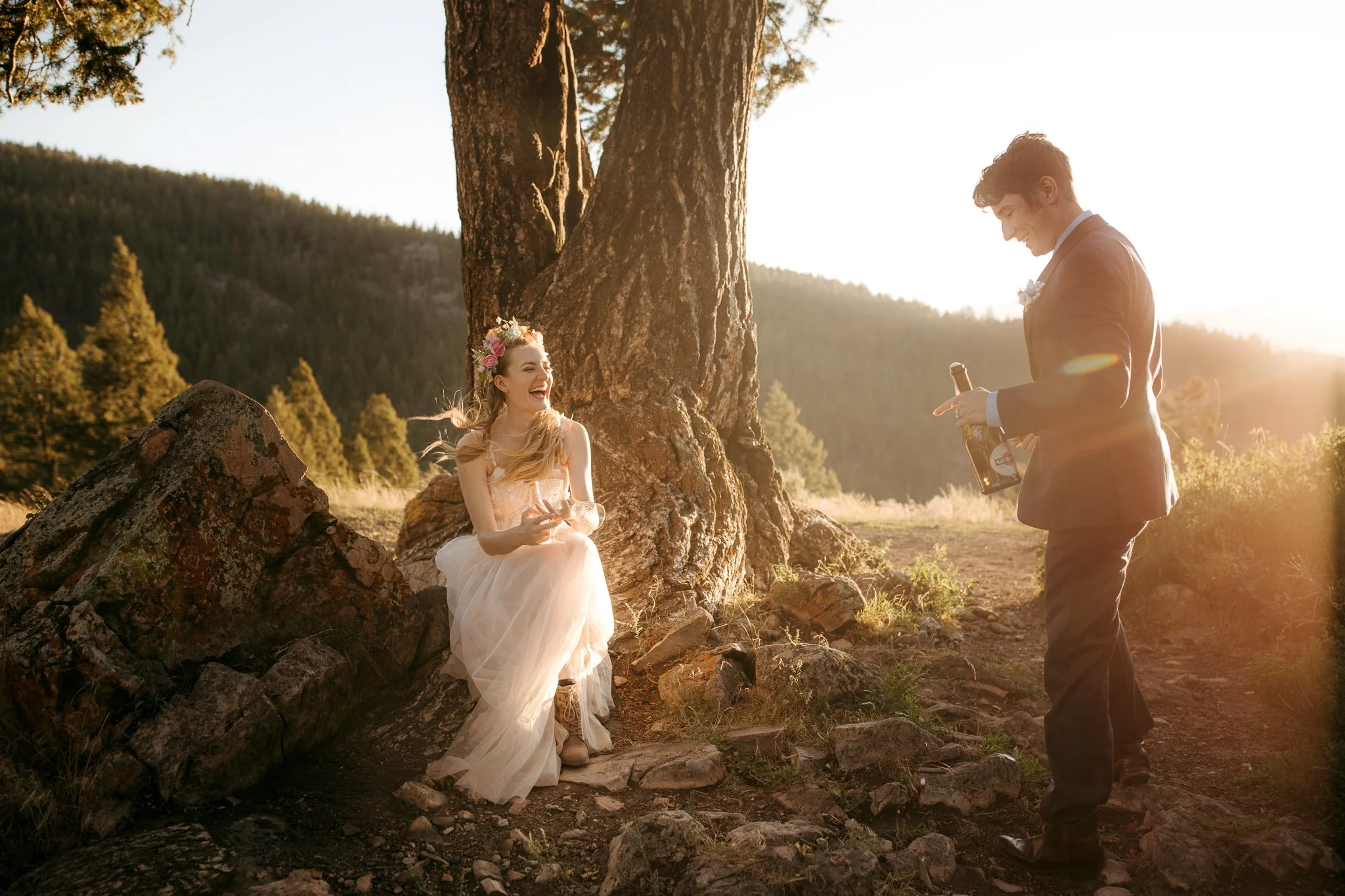 Couple celebrating with champagne at sunset in the mountains after their elopement ceremony