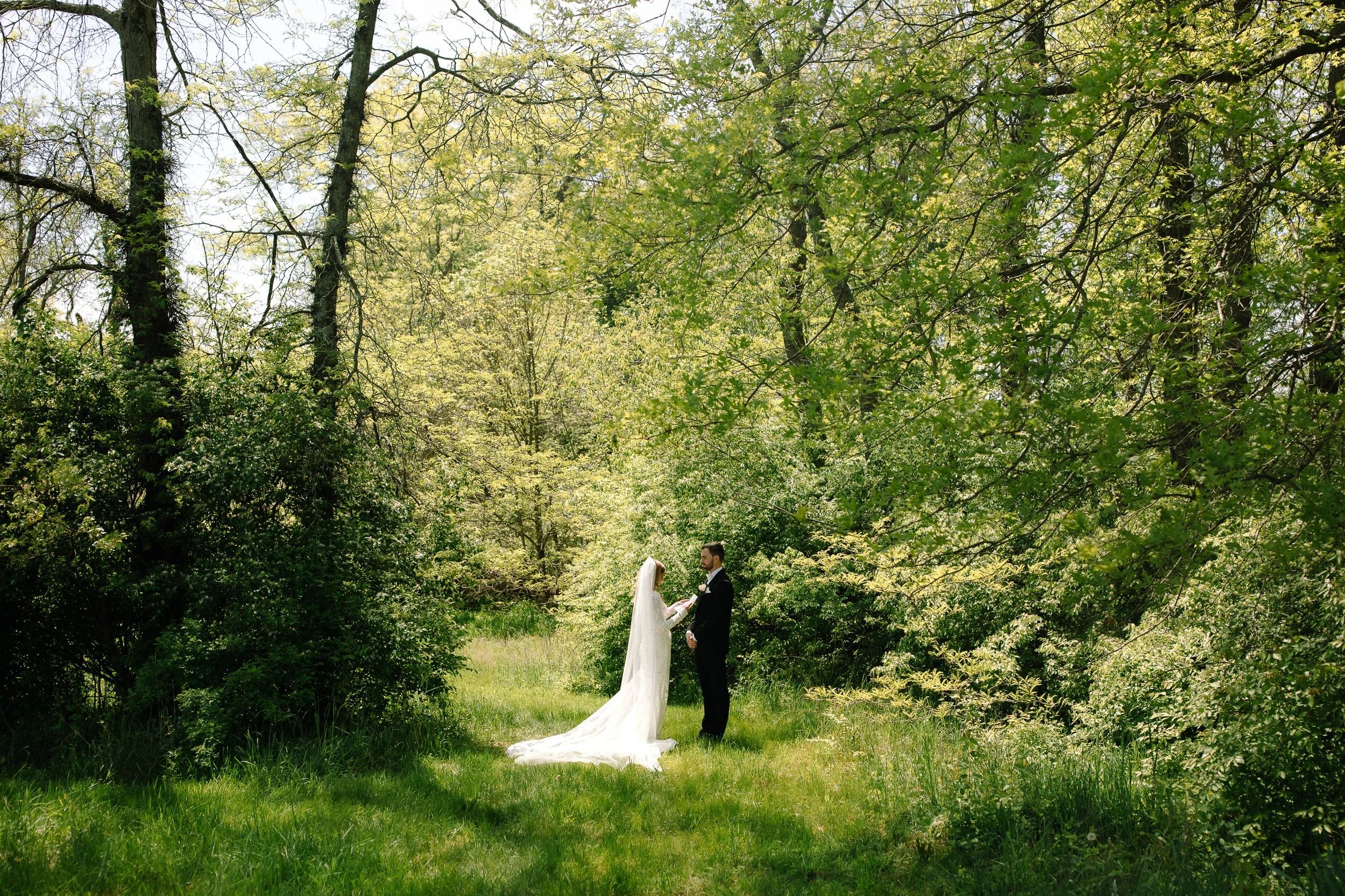 Bride and groom standing together in a green clearing during their spring wedding at Jorgensen Farm The Gardens in Columbus, Ohio.