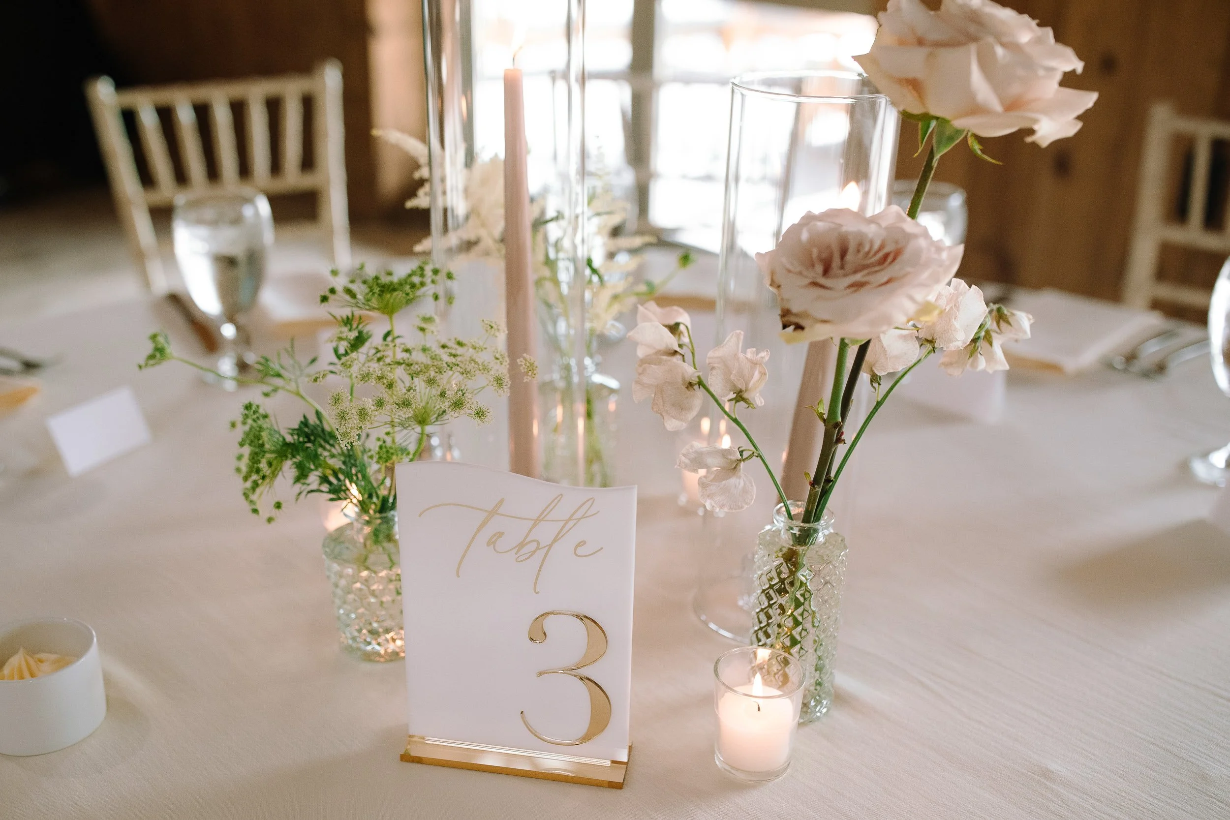 Candlelit reception table with soft pink florals inside the historic barn at Jorgensen Farms in Columbus, Ohio.