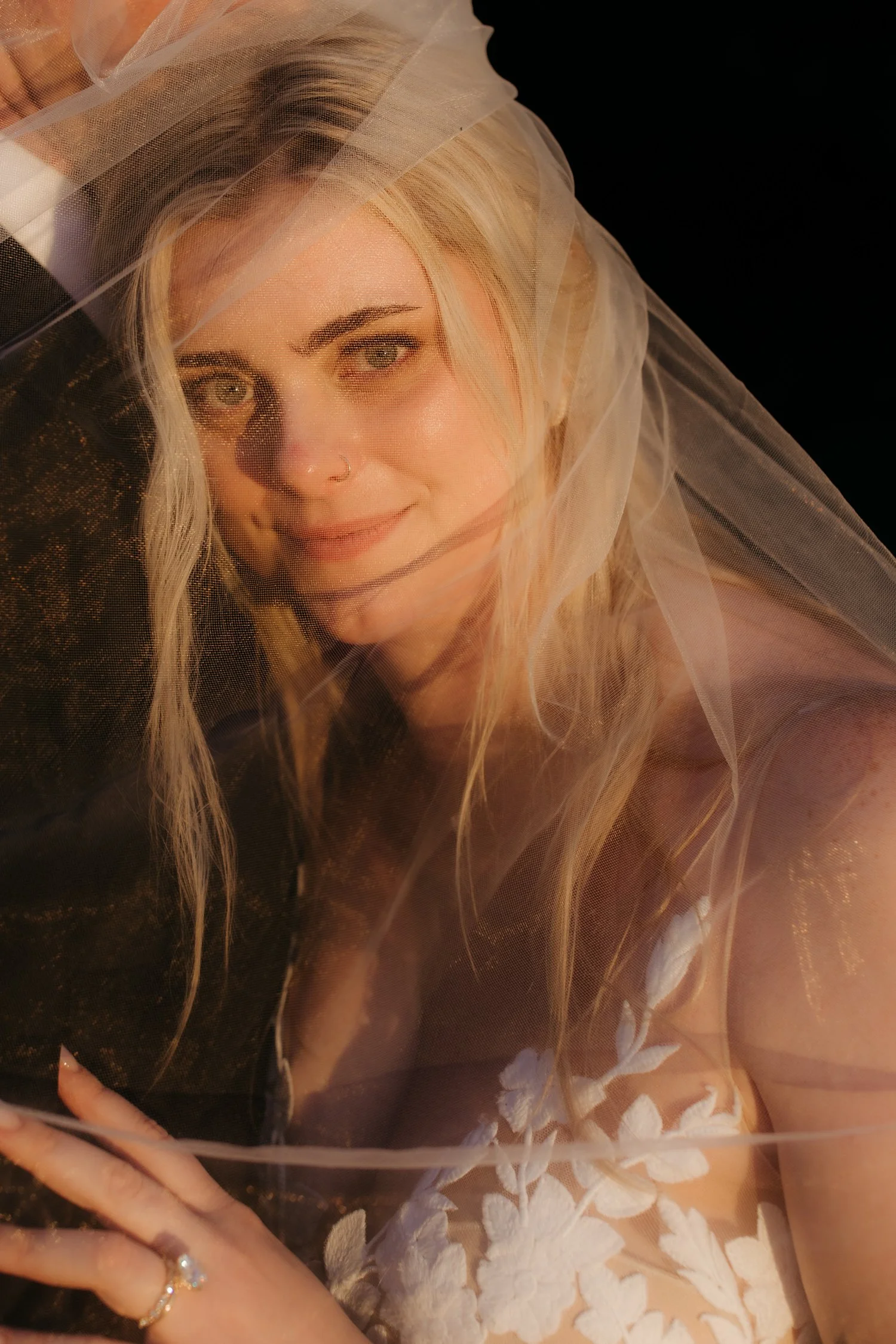 Close-up portrait of bride with veil catching golden light