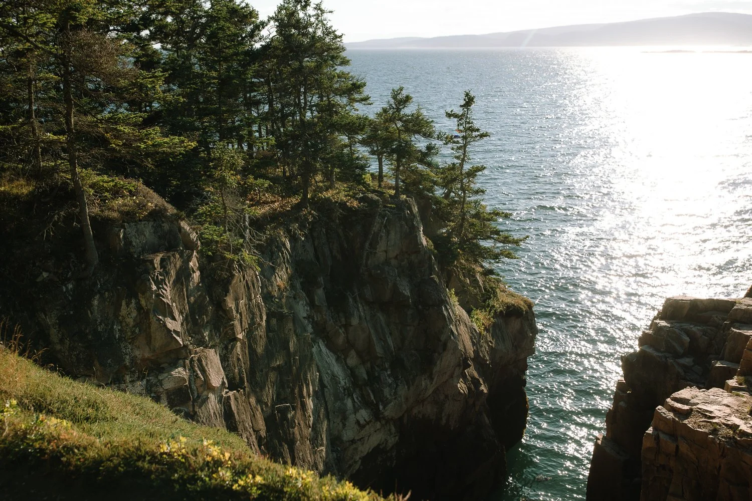 Dramatic coastal cliffs and ocean light during sunset along the Acadia National Park coastline