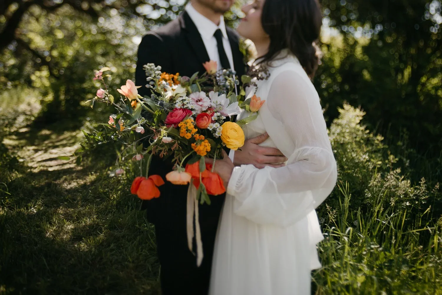 Couple embracing in garden during outdoor wedding portrait session with vibrant florals