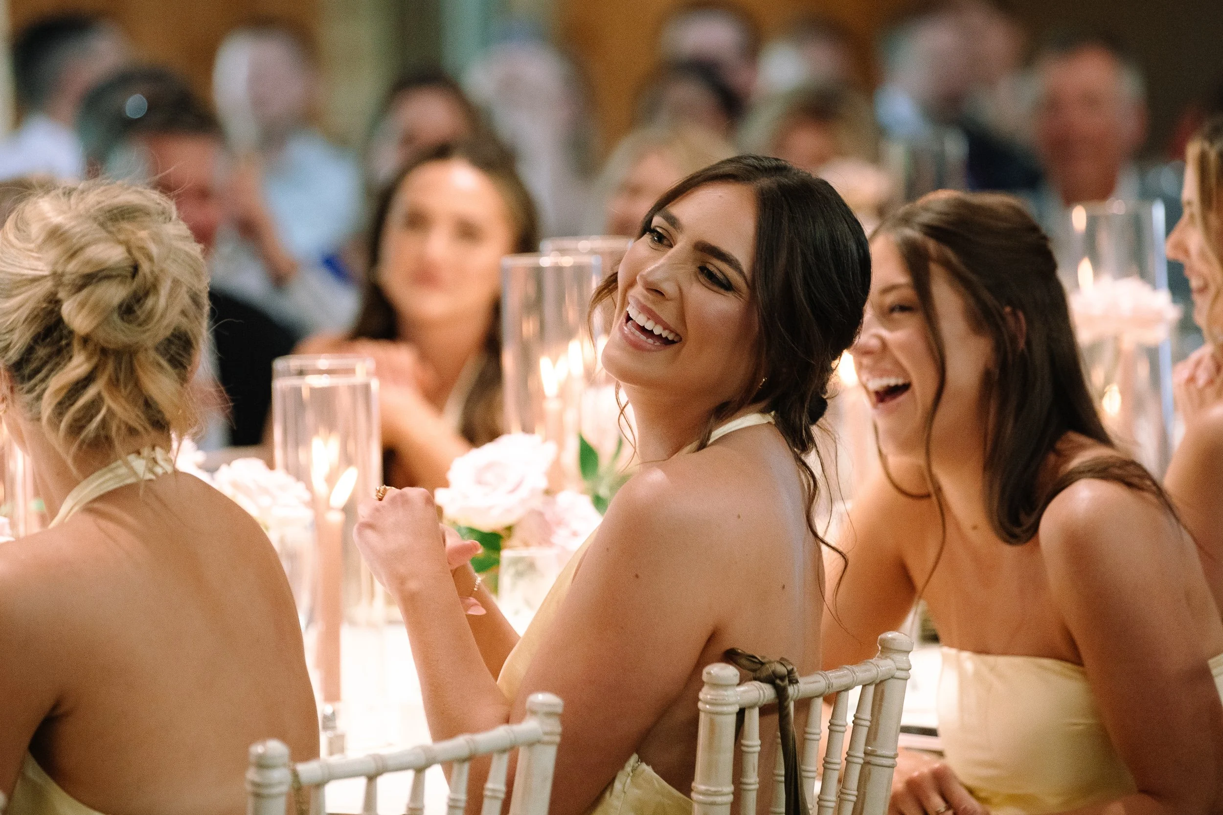 Guests laughing at candlelit reception tables inside the historic barn at Jorgensen Farms in Columbus.