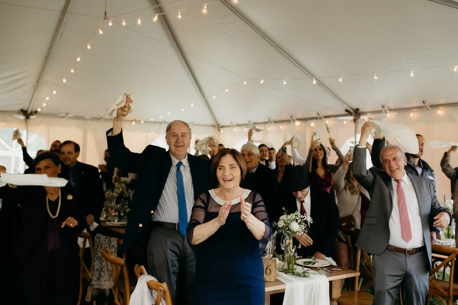 Wedding guests cheering during the reception inside the tent at Windrift Hall