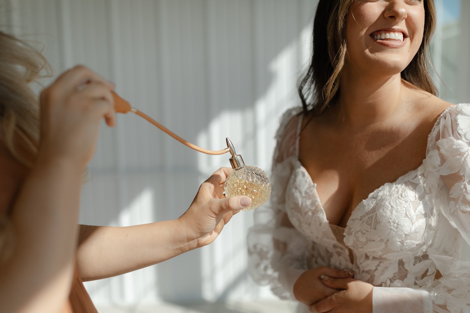 Bridal getting ready moment with a bridesmaid spraying perfume at an Ivory Meadows wedding in Yellow Springs, Ohio.
